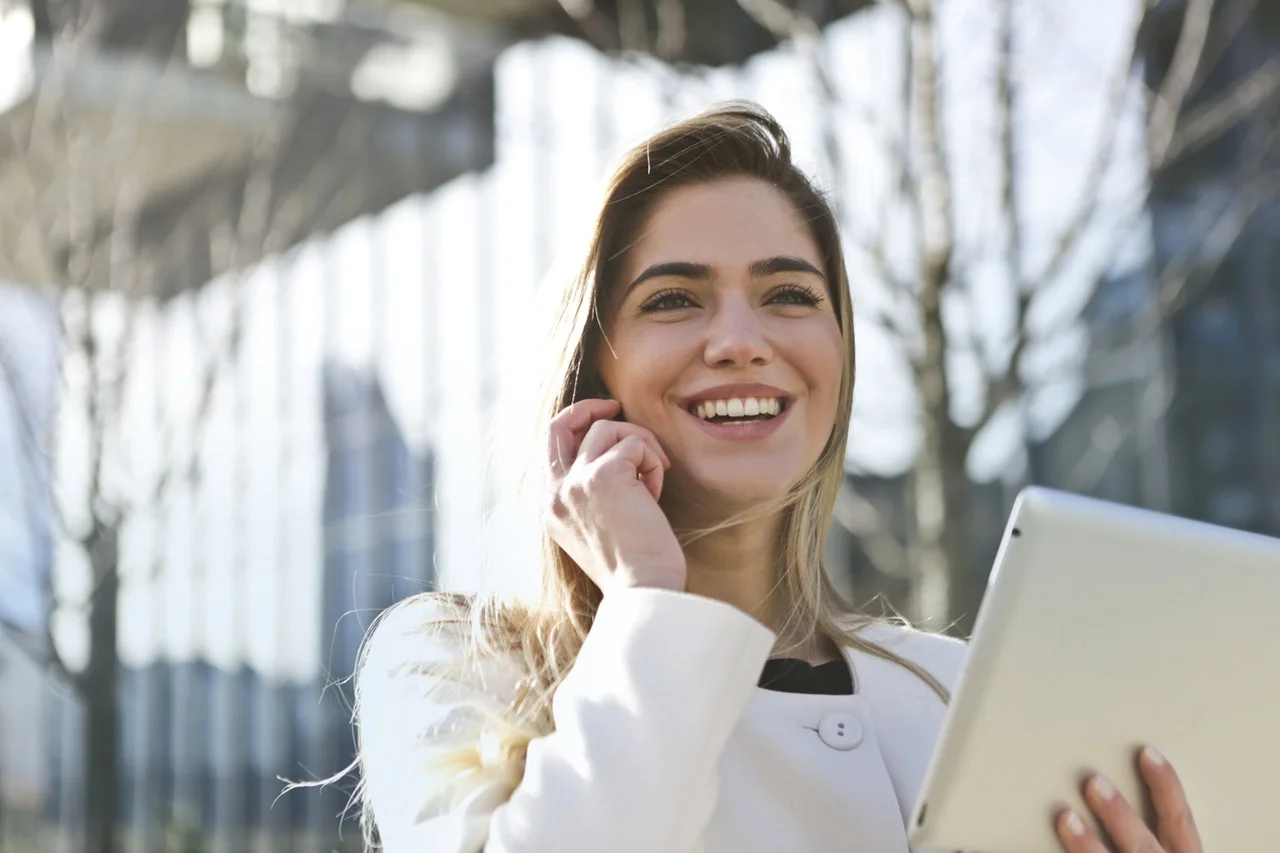 white woman smiling holding ipad
