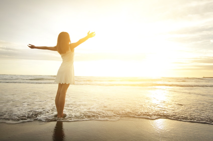 woman on beach with arms open