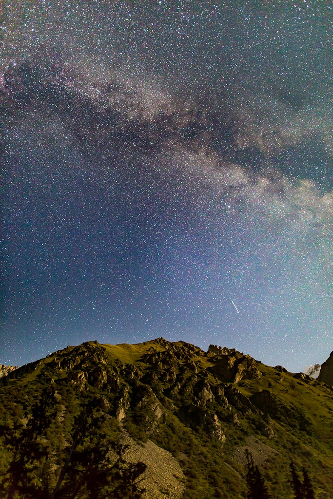 Looking due East, a satellite makes a bright streak over the hills; shooting stars do not have such continuous patterns. The moon makes the light from the right of the photo, dimly lighting the mountains.