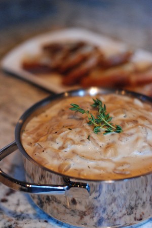 My sister and I made this French Onion Dip as an après-ski snack while I was visiting her in Park City, Utah in January. It came together quickly and was perfect with a glass of red wine and a warm fire. I love this dip because it has all the same deep, caramelized flavors as a bowl of French onion soup. We used beef stock in our version, but you can use chicken stock or water for a vegetarian option. The dip best when it’s hot, and we served ours in a little stainless steel pot to keep it warm. To mimic the bread that sits on top of French onion soup we made crostini with slices of baguette and melted Gruyère cheese, and they were perfect for dipping. Active Time: 45 minutes Makes about 3 cups Ingredients French Onion Dip 4 tablespoons butter 2 very large sweet onions, cut in quarters, then sliced into ¼-inch thick half moon slices 1 tablespoon garlic, finely chopped or grated ½ cup dry white wine ¾ cup beef stock, chicken stock or water 6 oz Philadelphia cream cheese, at room temperature 8 oz sour cream 1 teaspoon fresh thyme leaves, roughly chopped 1 teaspoon fresh lemon juice 1½ teaspoons salt ½ teaspoon pepper Thyme sprigs for garnish Gruyère Crostini 1 thin French baguette, cut into ½-inch thick rounds 1 cup finely grated Gruyère cheese ½ cup olive oil Salt Pepper Preparation French Onion Dip Melt the butter in large sauté pan over medium-high heat. Add the onions and cook, stirring occasionally, until the edges begin to turn golden brown. Add the white wine and turn the heat to medium, cooking until the onions are soft and the color of caramel, about 15 minutes. Add the garlic and cook until fragrant, 2 to 3 minutes. Add the beef stock and cook until the stock has reduced and the onions are deep golden brown and creamy, 6 to 8 minutes. Add the thyme leaves, lemon juice, salt and pepper. Cook for a minute or two to allow the flavors to blend. Add the cream cheese and stir until the cheese is soft and the onions are coated. Turn off the heat and fold in the sour cream. Transfer to a serving bowl and garnish with fresh thyme. Gruyère Crostini Preheat the oven to 375° F. Place the baguette slices on a baking sheet and drizzle with olive oil. Sprinkle salt and pepper over the bread. Toast the crostini until lightly golden brown, about 10 minutes. Remove the baking sheet from the oven and top each crostini with a little grated Gruyère cheese. Bake for another 2 to 3 minutes, or until cheese is melted. Serve crostini on a platter along side the French Onion Dip.