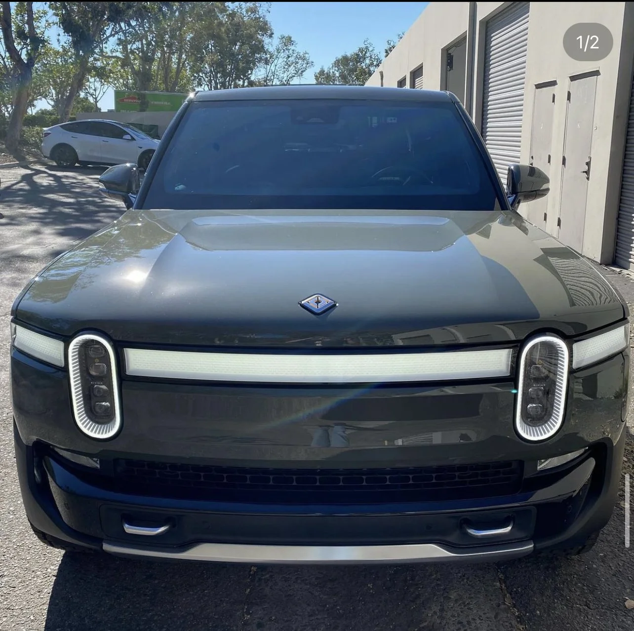 Front view of a black electric SUV with a unique headlight design and a horizontal LED light strip across the front