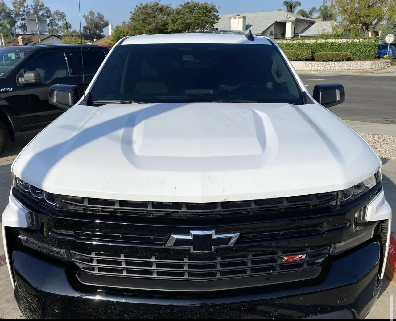 Front view of a white Chevrolet truck parked outside, with a black grille and Chevrolet emblem, and an 'Z71' badge on the grille.
