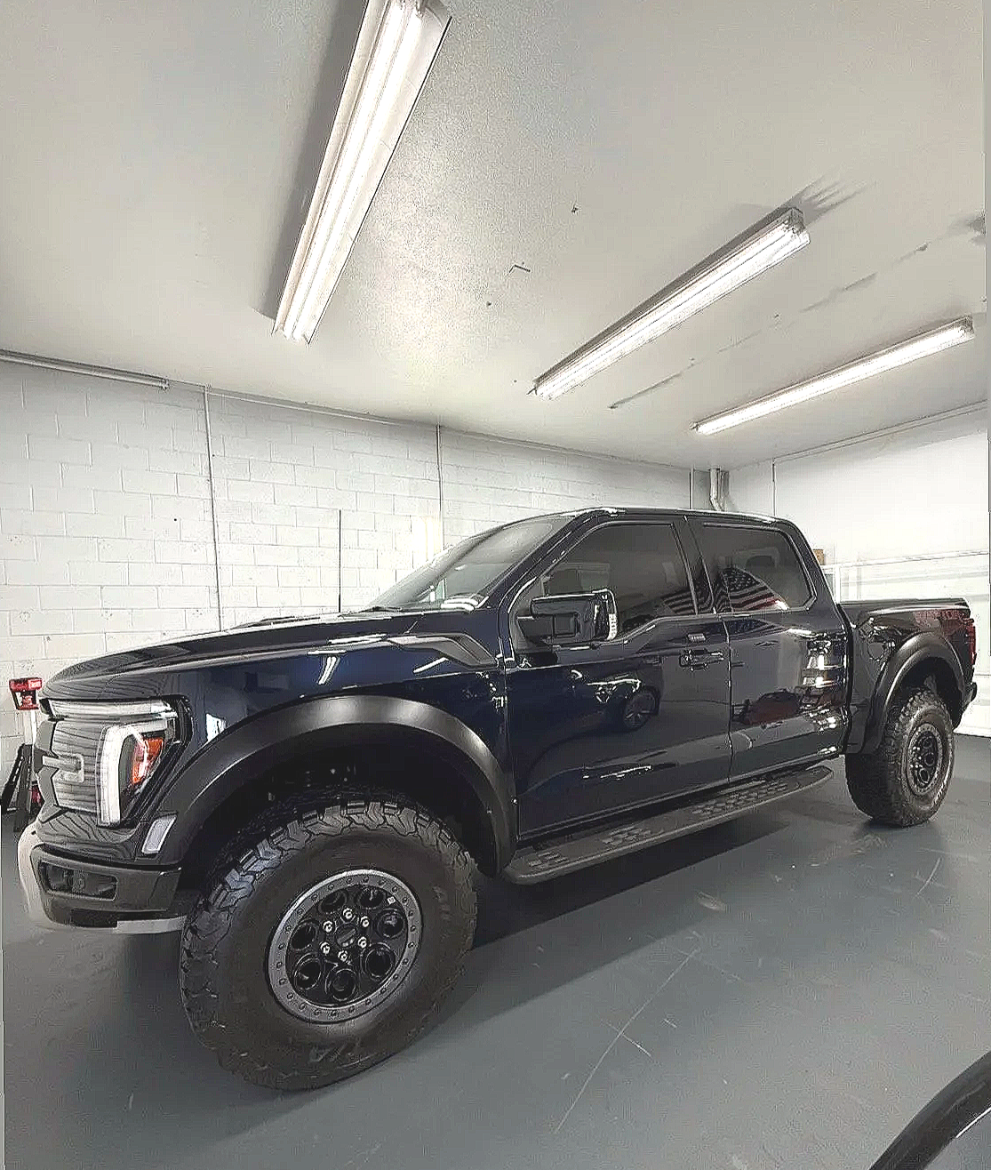 Close-up of the front part of a black pickup truck, showing the headlight and grille after ceramic coating by honest tint in Yucaipa ca. 