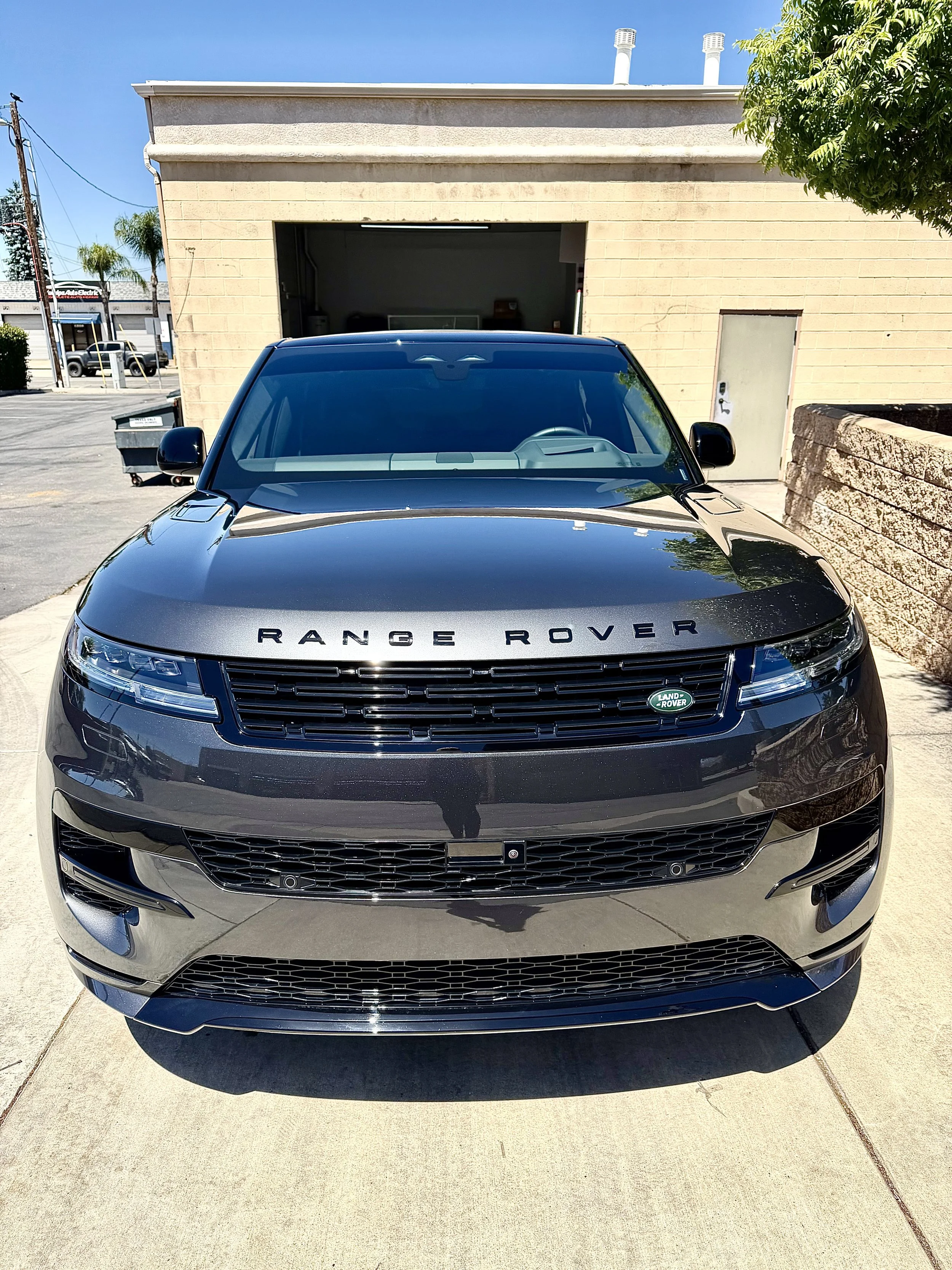 Black Range Rover SUV parked in front of a building with an open garage door on a sunny day.