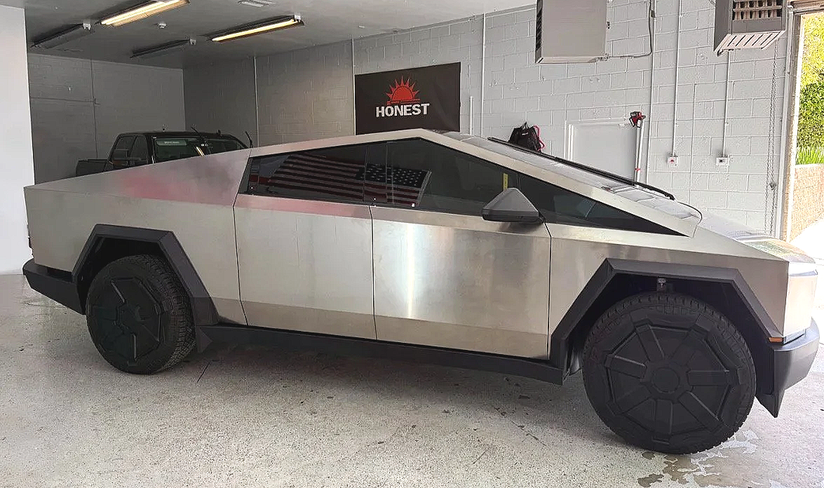 A futuristic, angular Tesla Cybertruck parked inside a garage with a black and white