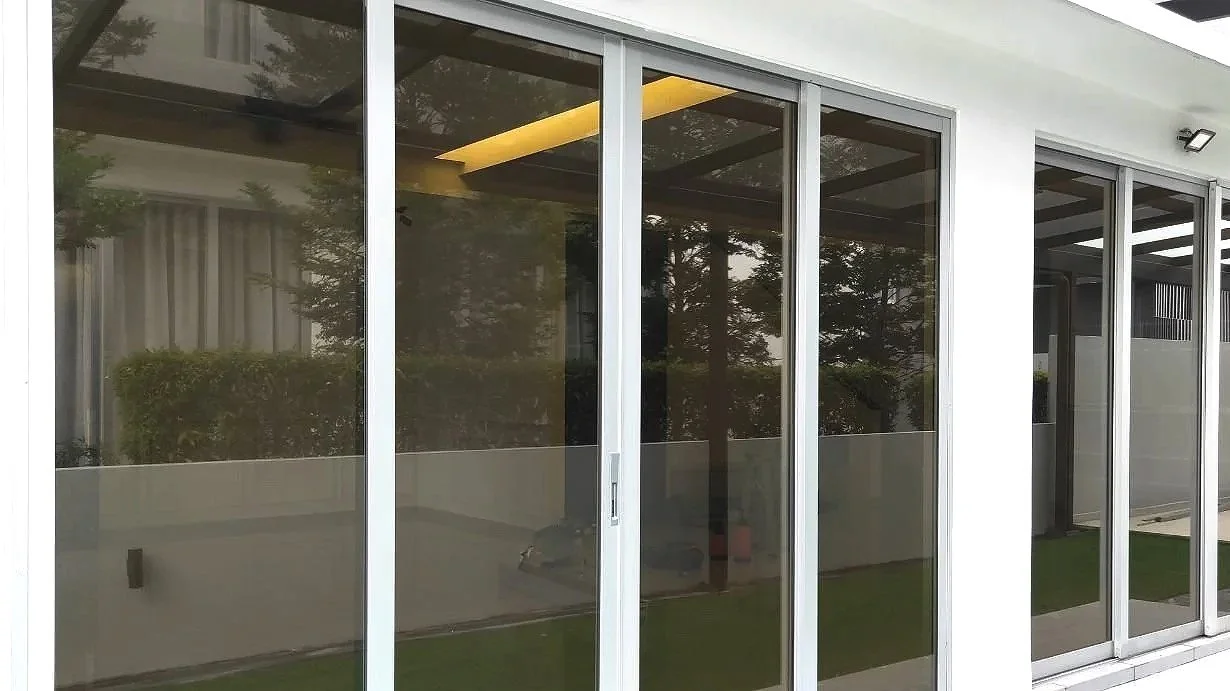 Glass sliding doors with white framing on modern building exterior tinted with window film installed by honest tint and ppf located in yucaipa ca.