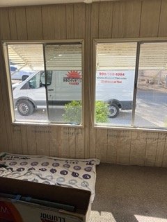View through two windows showing a truck parked outside with a red logo and some greenery inside.