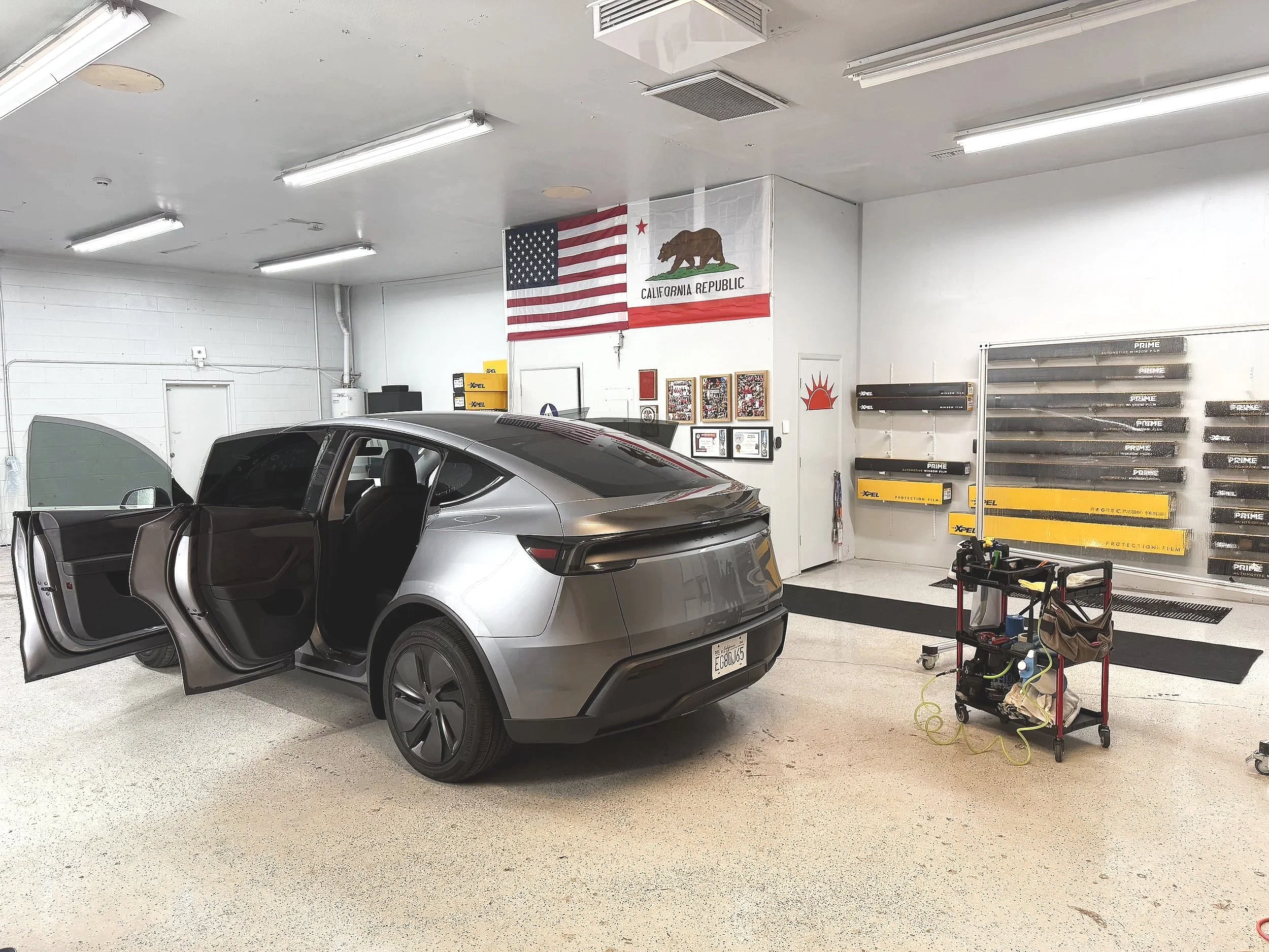 White Tesla Model 3 with Llumar IRX window film installed by Honest tint and ppf located in yucaipa ca. driving on the road during daytime with a blue sky and trees in the background. 