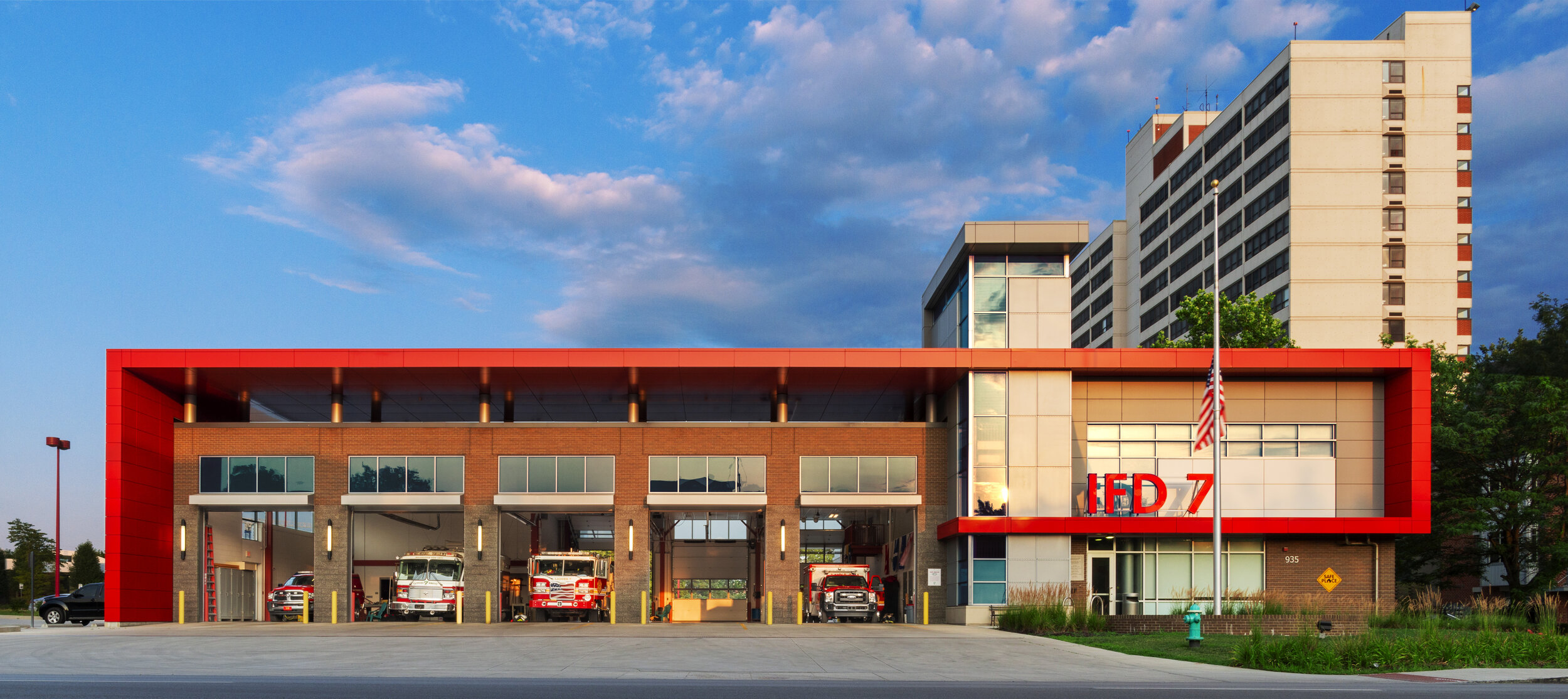 An architectural photography showing a building with several fire trucks.