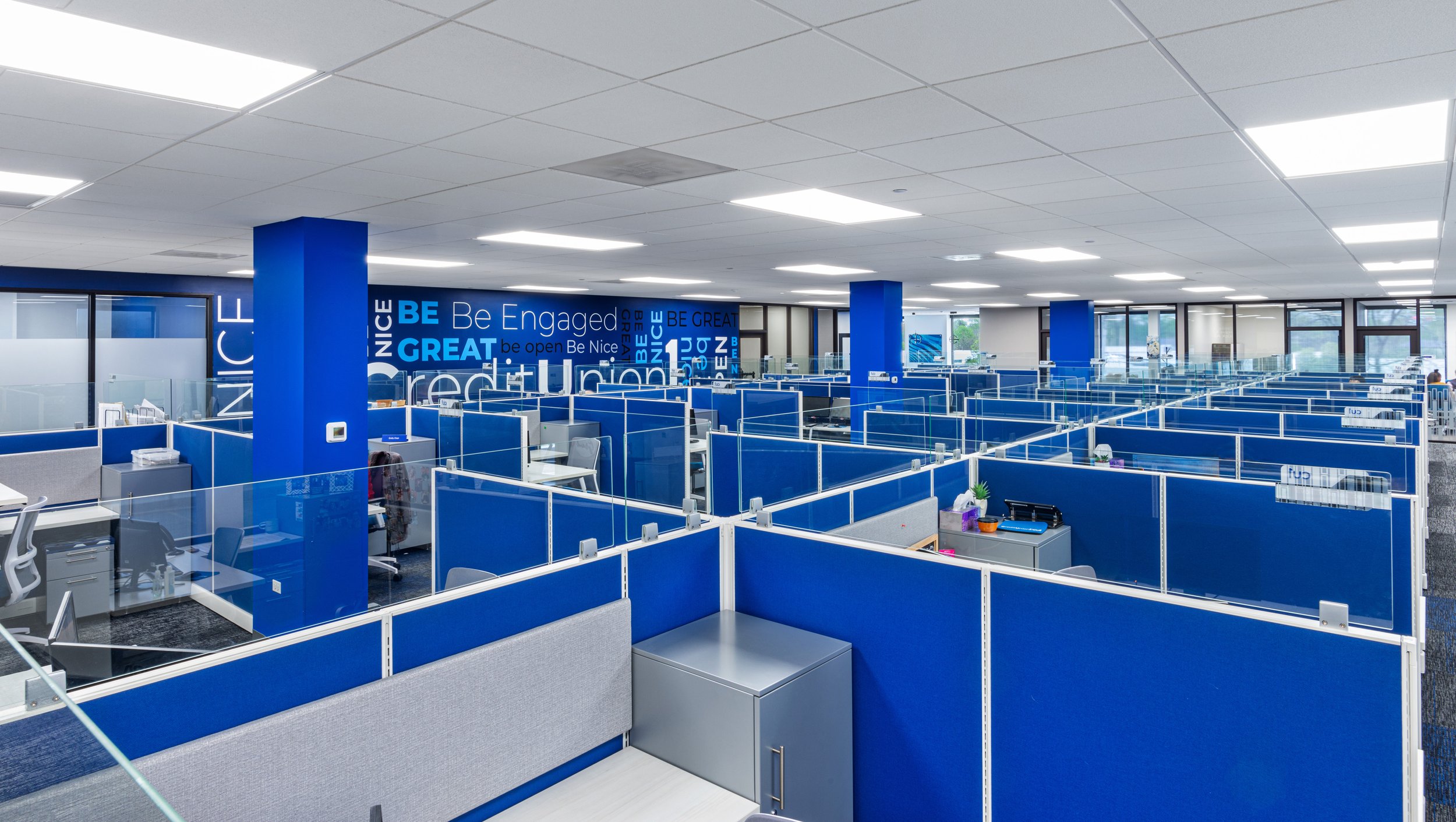 Commercial photography of a big blue office room with lots of desks ordered in great precision.