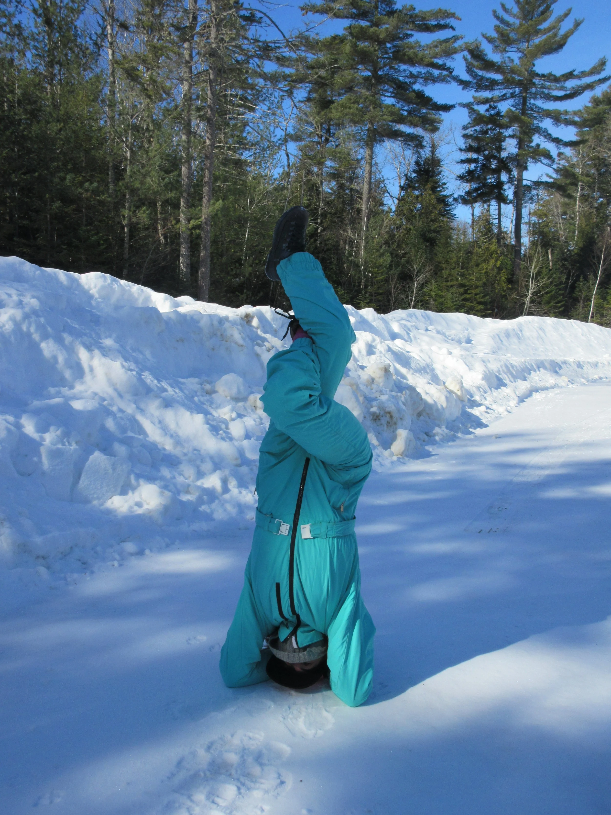 Yoga student doing a headstand in the snow on yoga retreat in Rangeley Maine