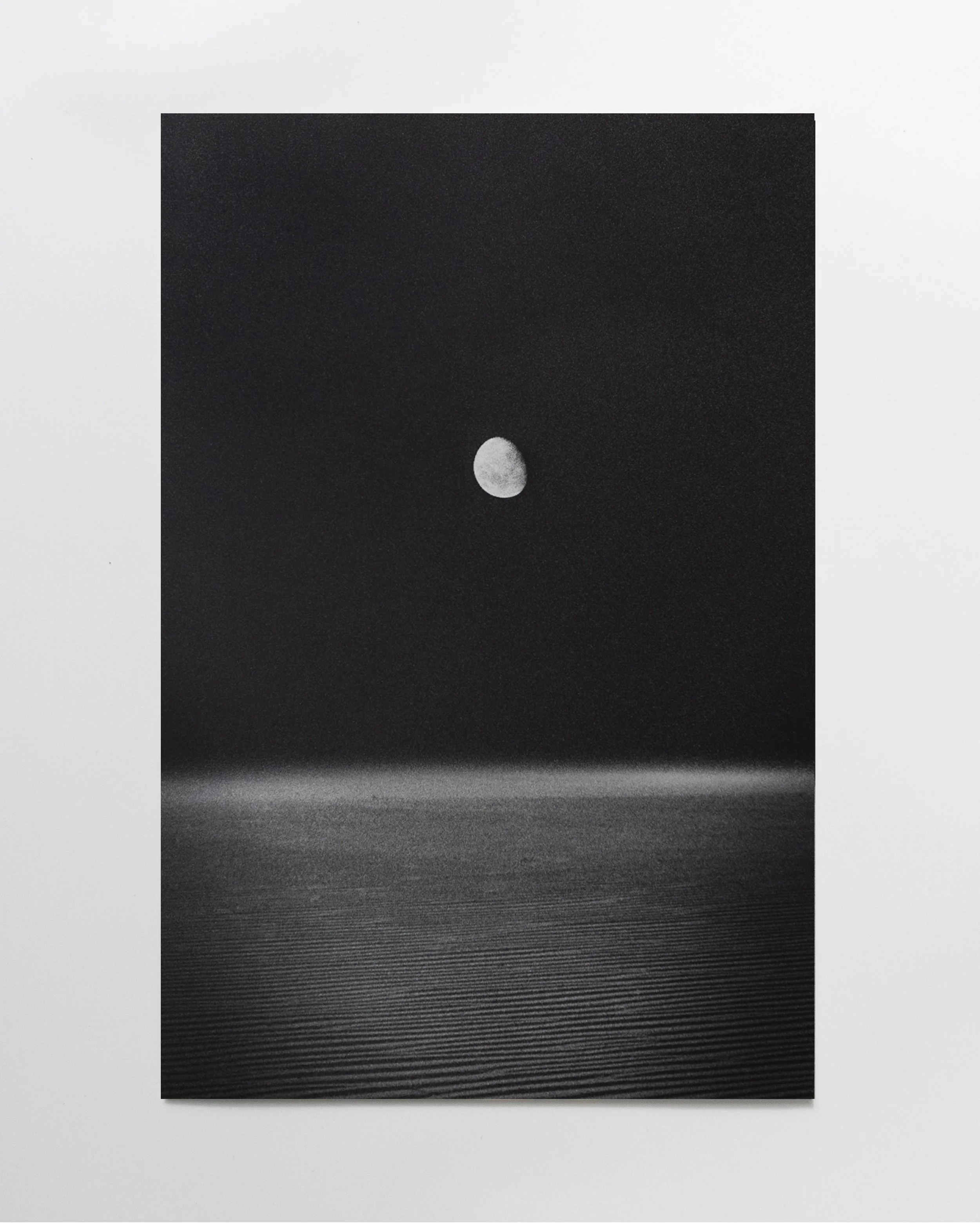 Black-and-white photograph of the moon over a water body with ripples