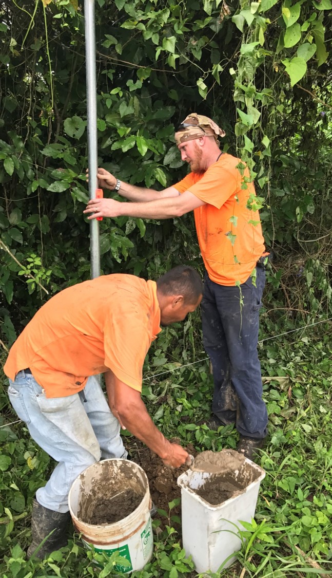 Barry and Edwin cementing in a fence pole