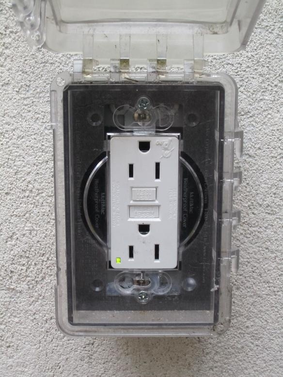 This GFCI in the outdoors has a plastic cover which closes to protect it from water.