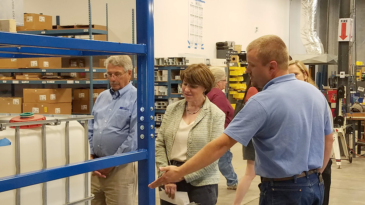 Jordan Honnette explains the workings of a Kahler Automation high-speed tote filler to Sen. Klobuchar.