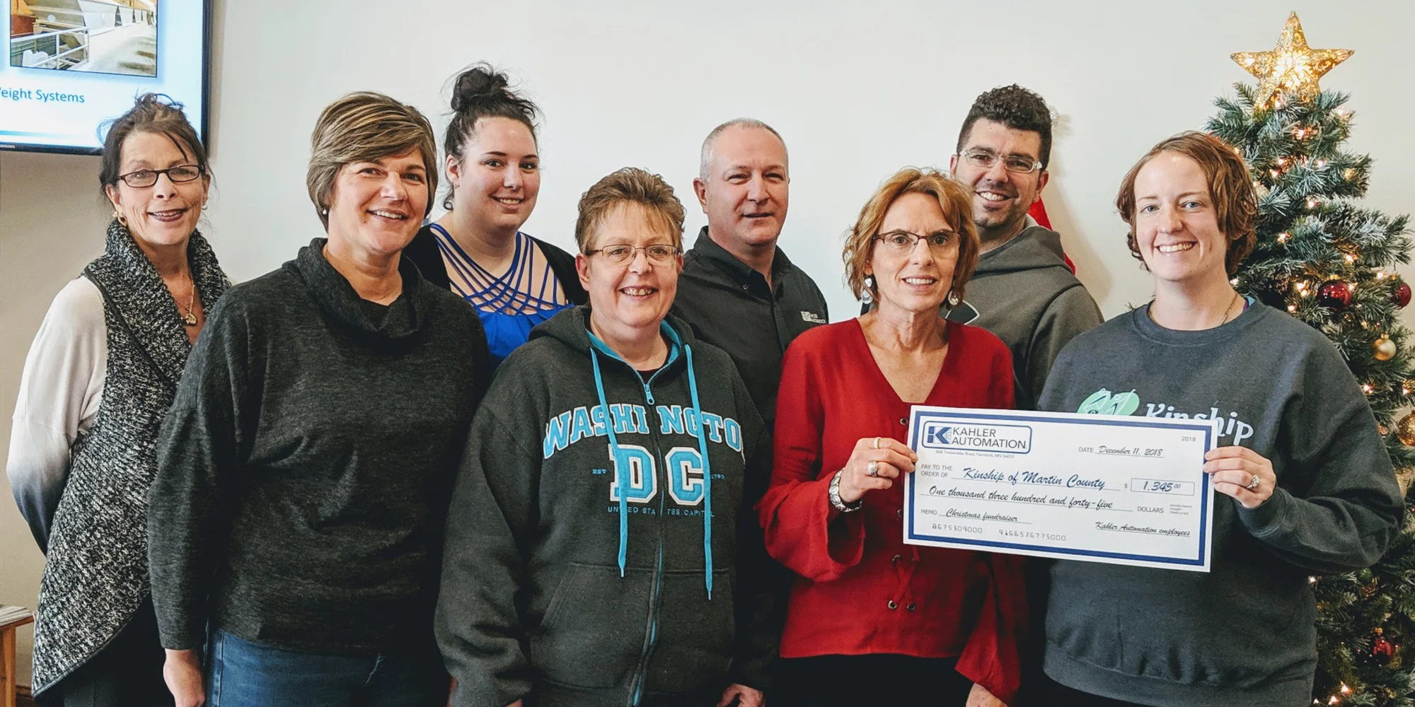 KINSHIP OF MARTIN COUNTY ACCEPTS CHECK FROM KAHLER AUTOMATION’S “BISON COMMITTEE” MEMBERS — L-R: Martha Myren, Courtney Cutler, Megan Hancock, Darla Mammenga, Brian Enstad, Norma Seibert, Max Haake, and Kinship of Martin County associate director Jen Kahler.