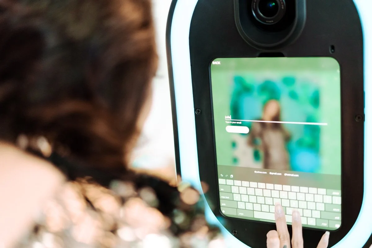 Person at a self-service kiosk, typing on a virtual keyboard with a colorful blurred background on the screen.
