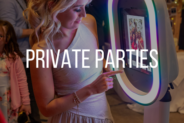 A woman using a photo booth at a private party, with a colorful illuminated frame around the screen.