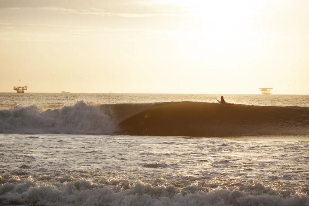 Harold Koechlin paddles over a wave at Lobitos, oil platforms visible on the horizon. Photo: Gary Parker.
