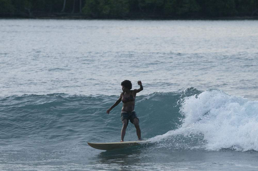 A new mum finishes breast feeding and heads out for a quick wave before dusk on the village's newly donated surfboard.