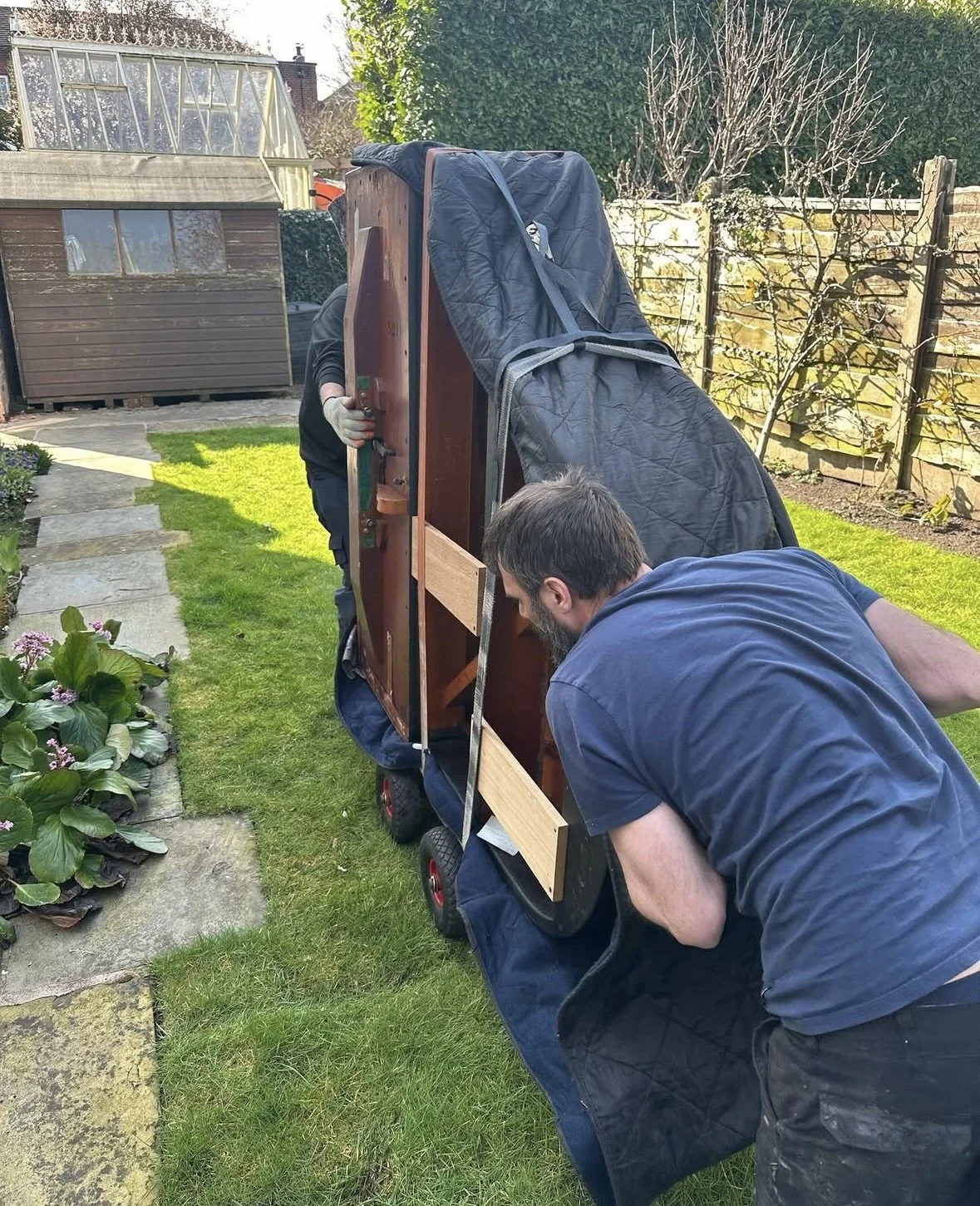 Two people moving a grand piano