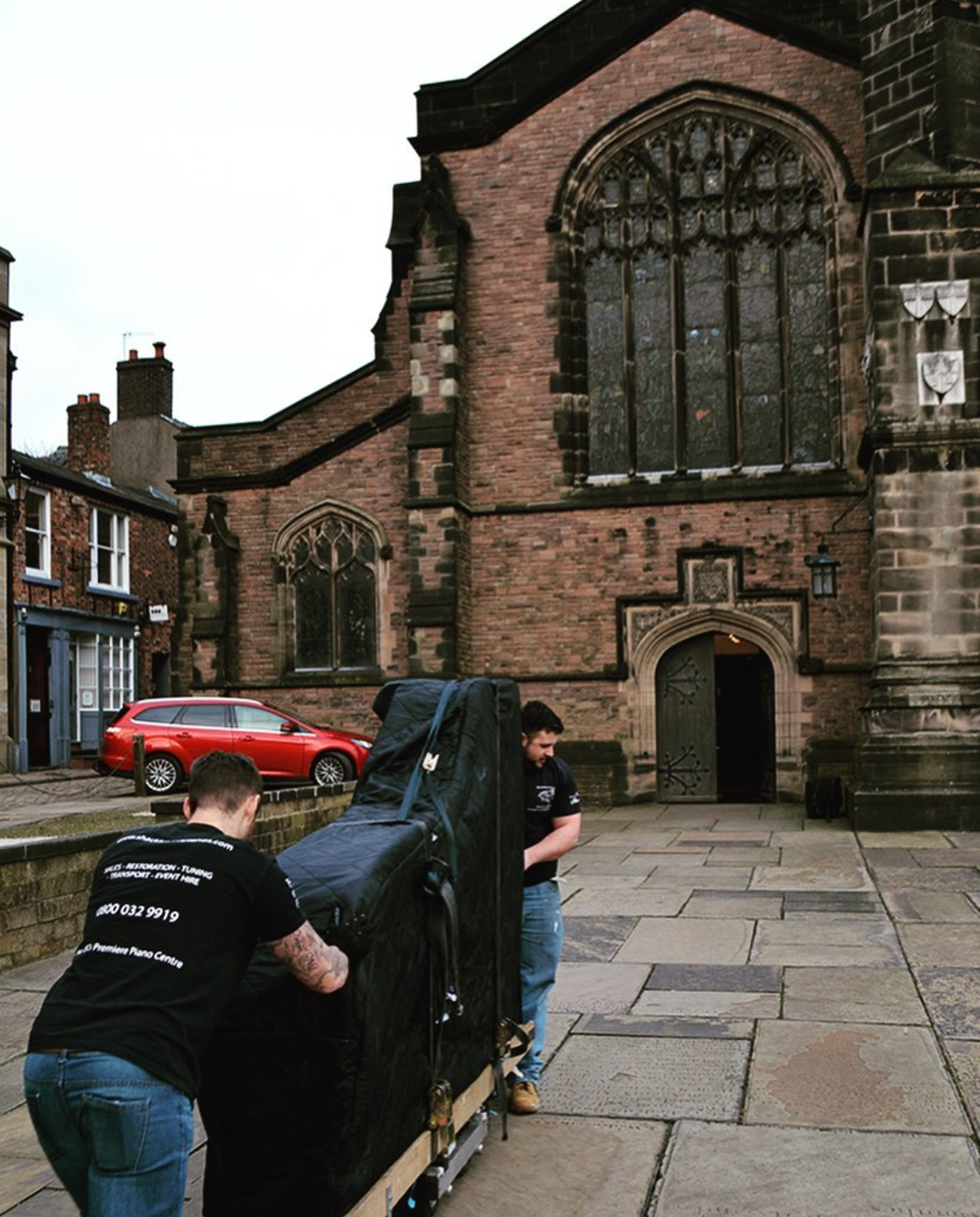 Grand piano being taken into a church for hire