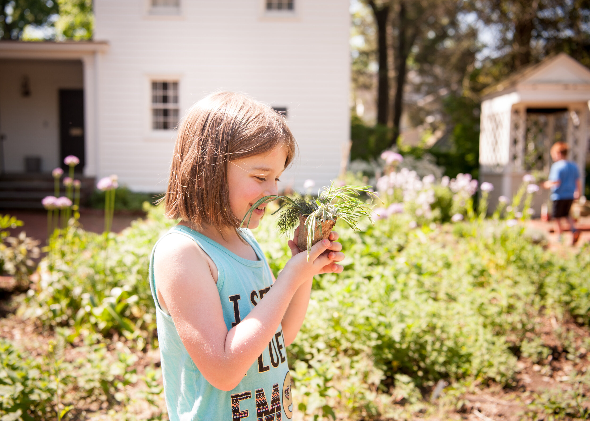  Young girl holding potted plant with wonder, in Landsberger Learning Garden 