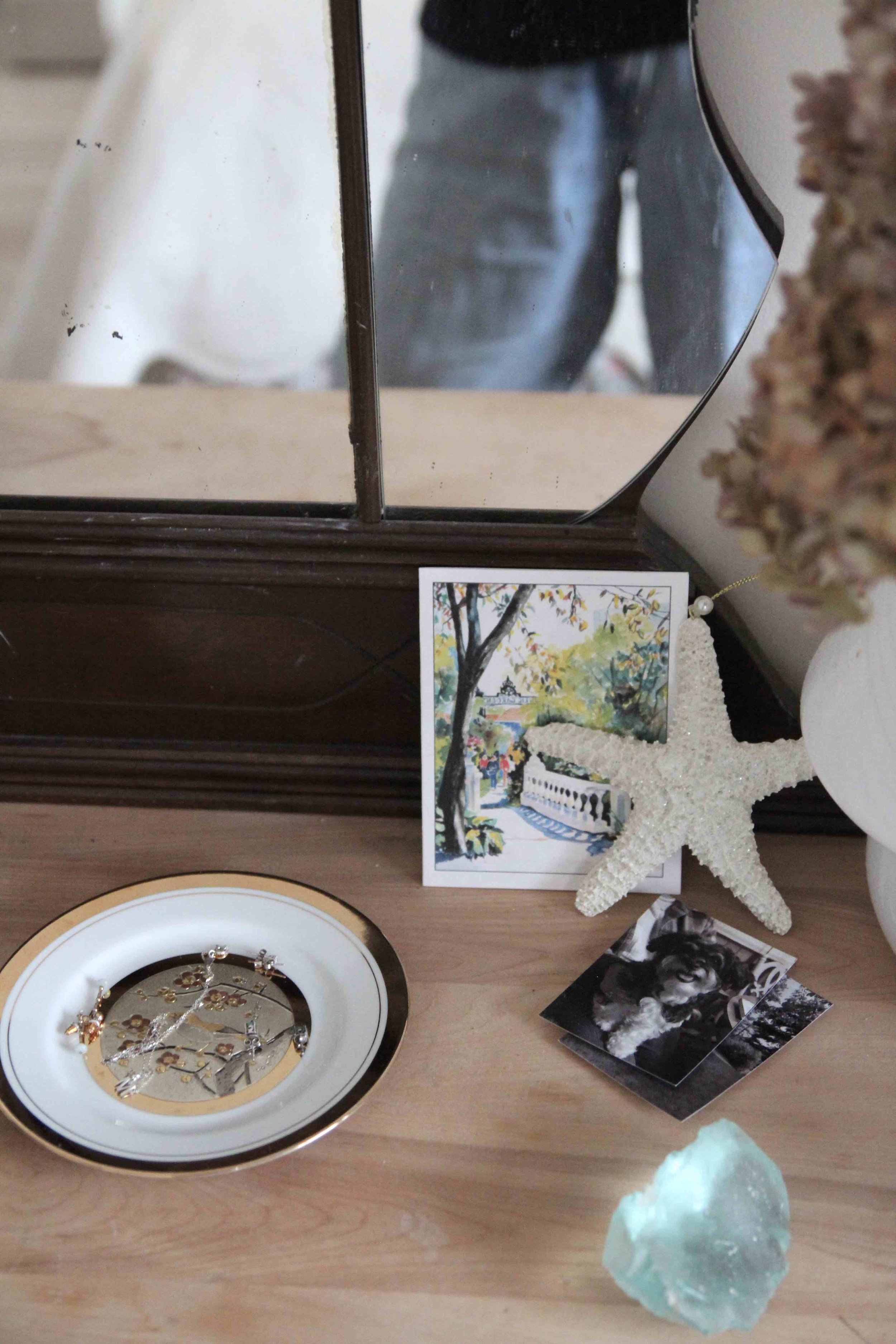 A curated intentional corner featuring a Robin bird jewelry dish, a starfish ornament, and sentimental photos. A symbolic space designed for throat chakra healing and reclaiming one’s voice in 2026.