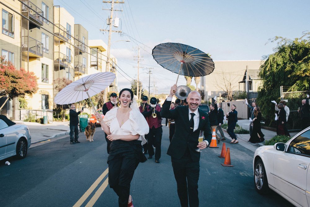 a just-married couple lead a parade around the block of their reception