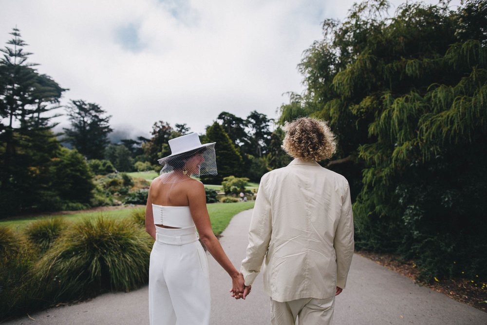 a bride and groom walking through the san francisco botanical garden.