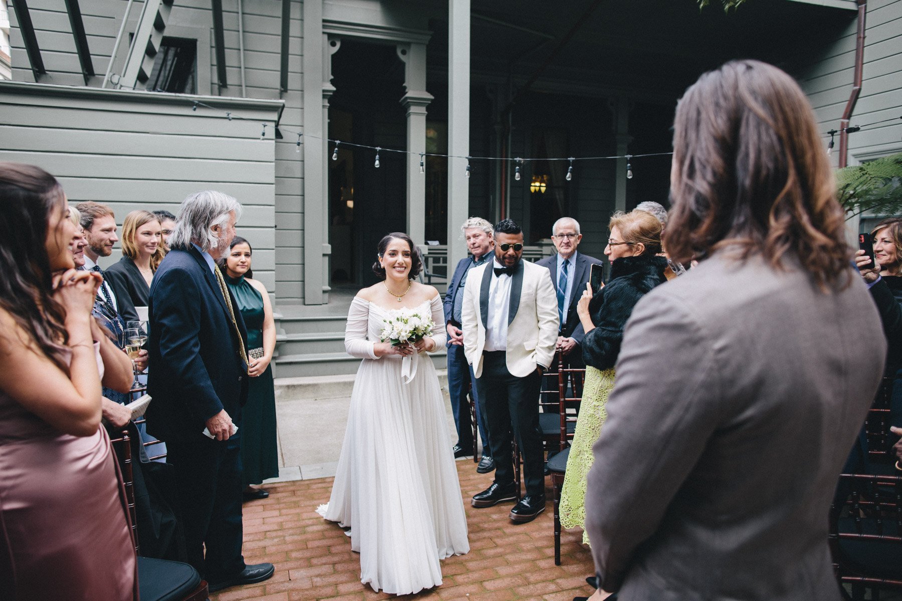 Bride walks down the aisle in the backyard of the Haas-Lilienthal House