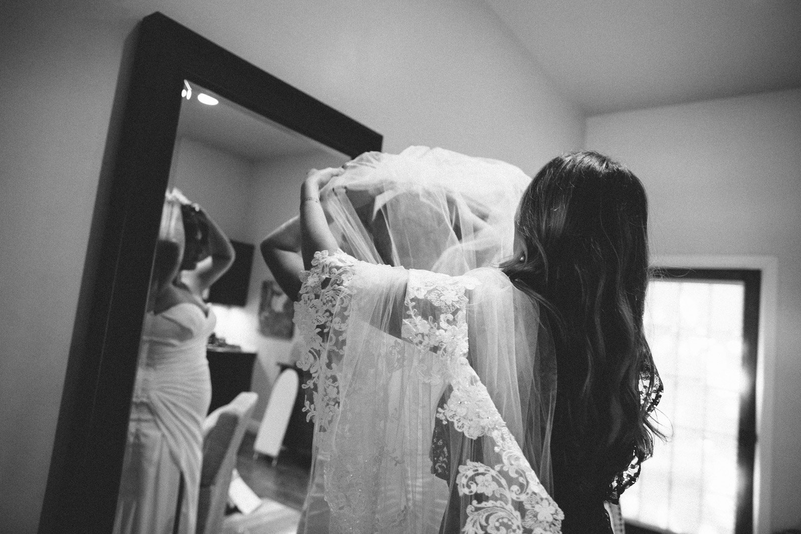 Friend helps bride put on her veil in Mendocino