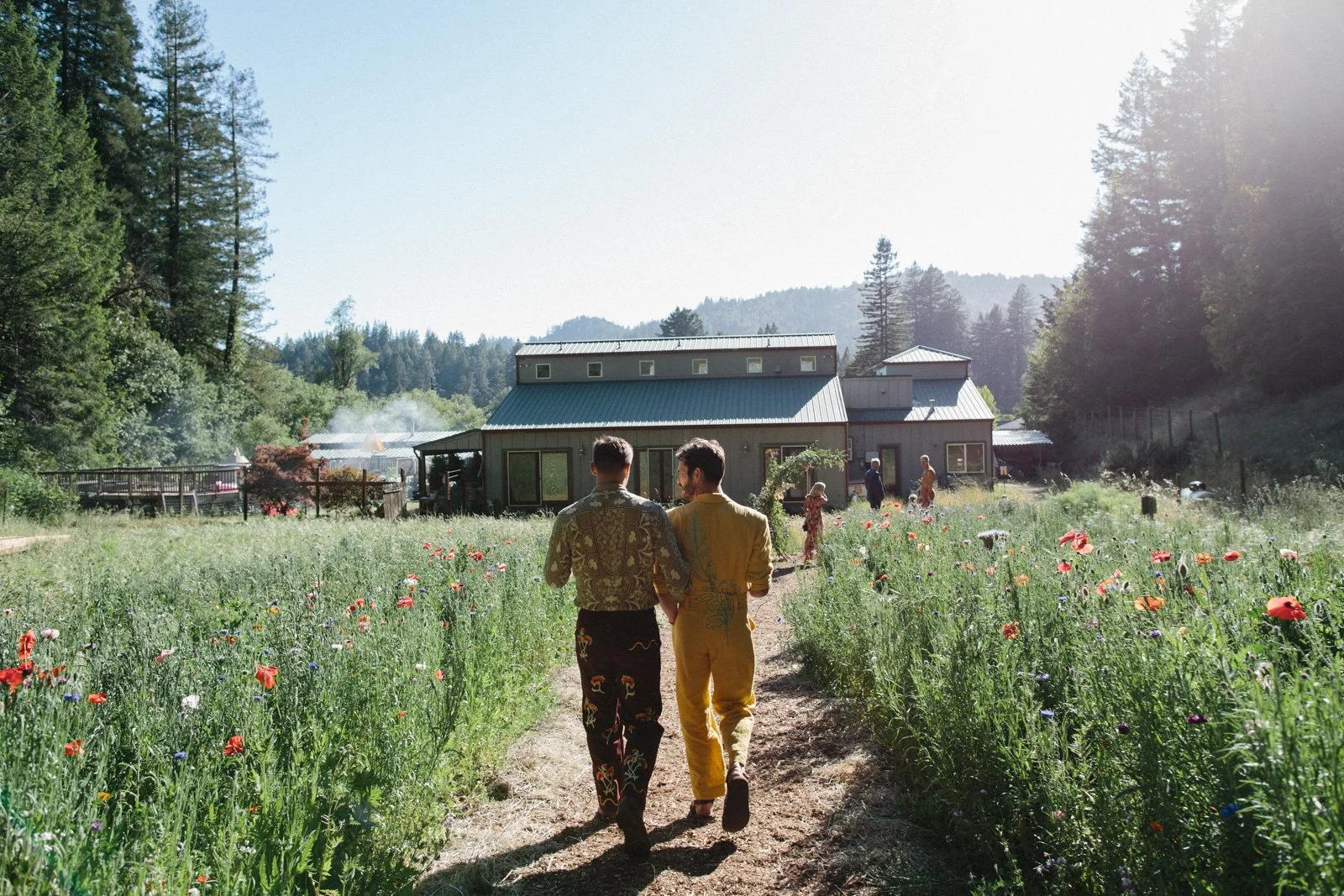 Grooms leaving their wedding ceremony through wildflowers at Solar Punk Farms