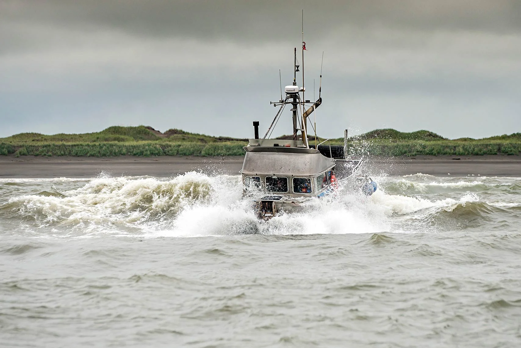 A gillnetter crosses through the breakers to make it out to the fishing grounds. Bristol Bay is interweaved with many sandbars and shoals, and fishermen use the area's many channels to enter and exit protected waters to access the fishing grounds.