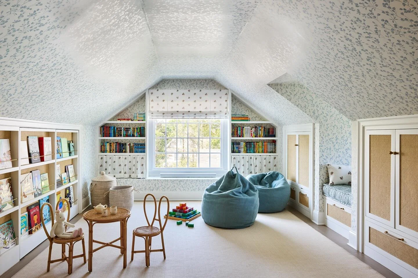 A third floor attic transformed into an idyllic playroom with clever uses of space by building millwork in unused attic eaves, reading nooks in deep dormer spaces and lots of bookshelves at the Montessori wall and flanking a (new) oversized picture w