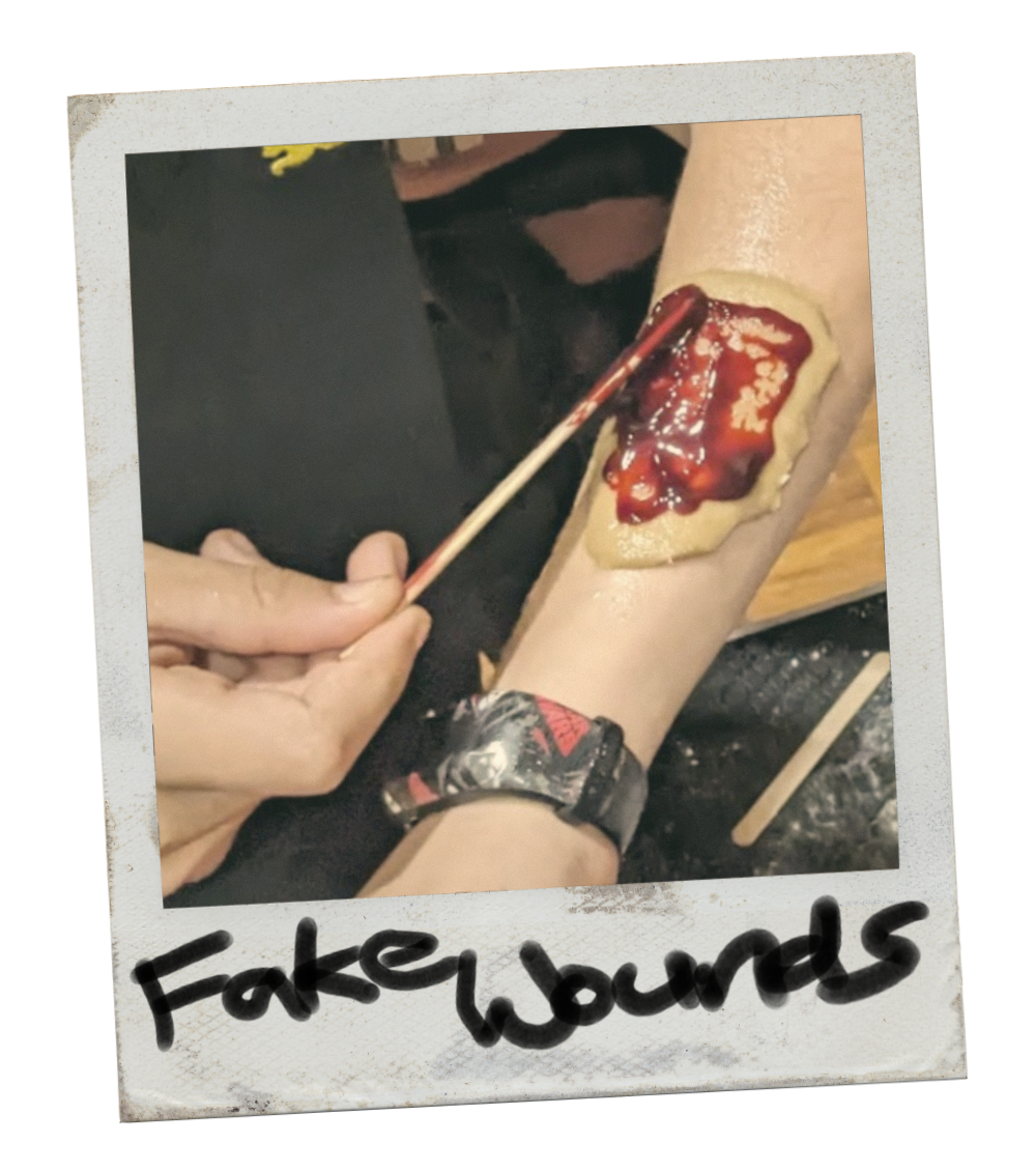 Close-up of a person's arm with a fake wound made of dough and fake blood to mimic a bloody wound, with the words "Fake wounds" written at the bottom.