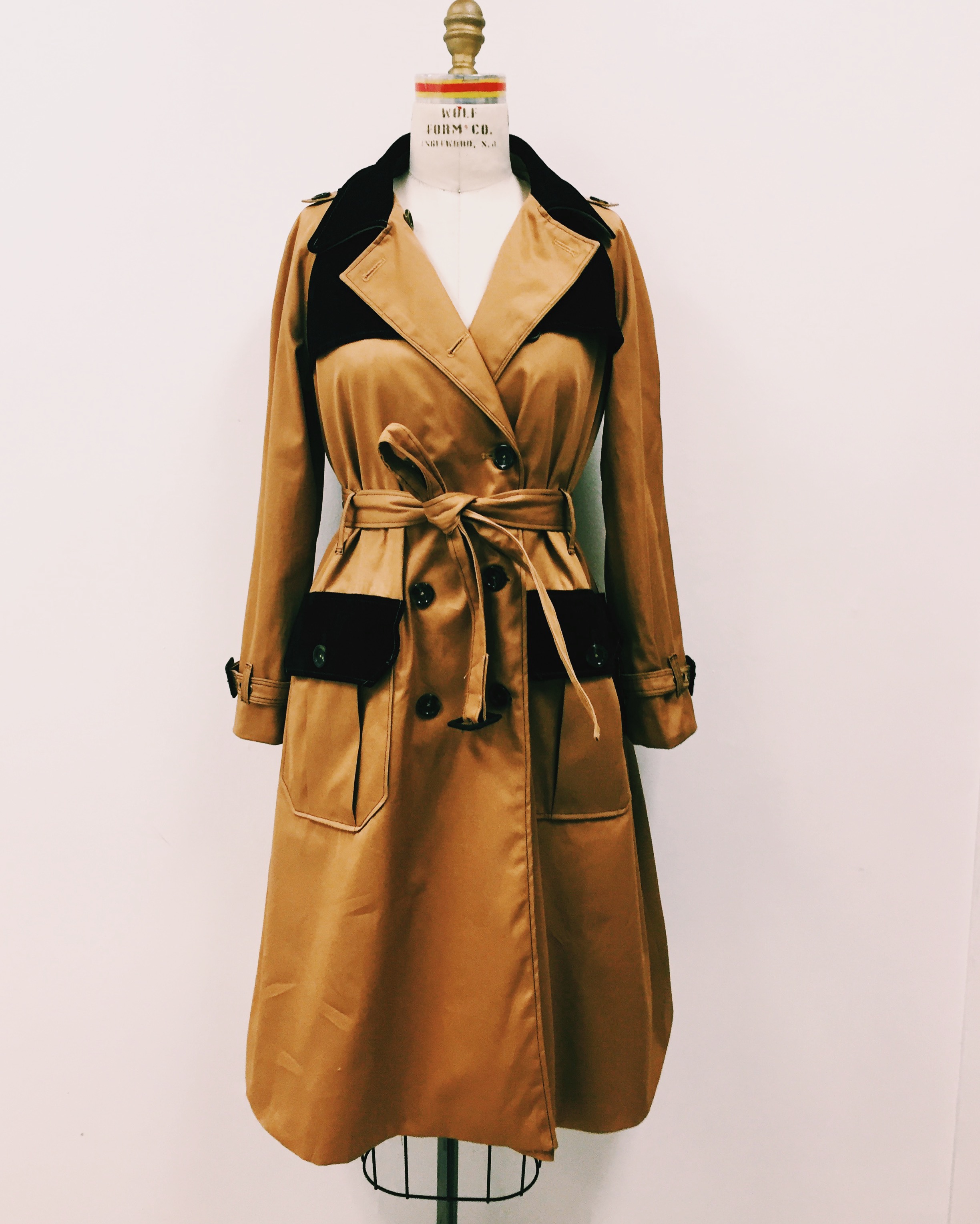  THIS PIECE IS A TAN TWILL TRENCH COAT WITH BLACK SUEDE DETAILS. THIS JACKET IS DOUBLE BREASTED AND HAS SUEDE GUN FLAPS, RAIN GUARDS AND POCKET COVERS. BELTS ON BOTH THE WAIST AND THE WRISTS.&nbsp; 
