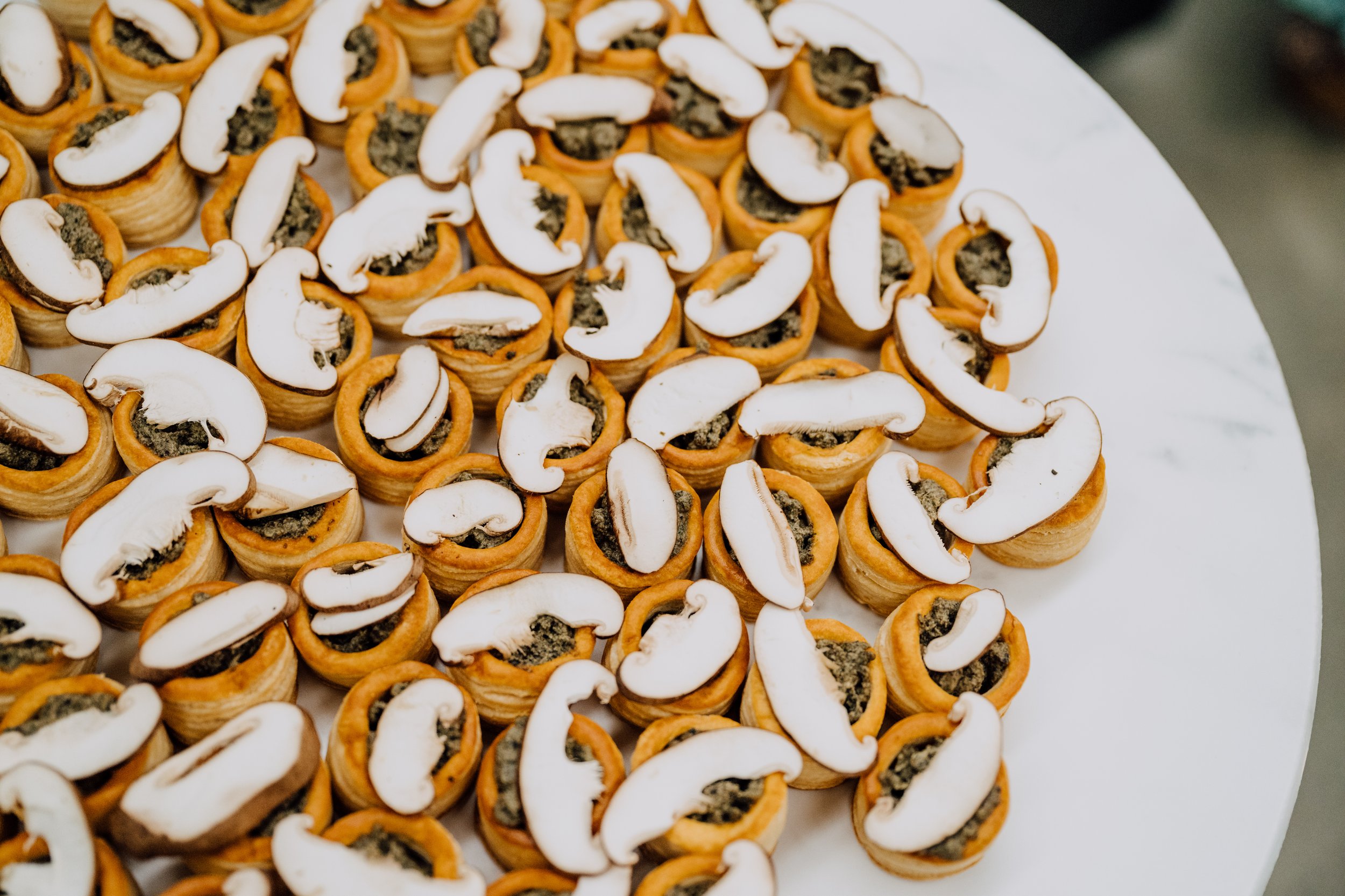 Pastry shells filled with spinach and topped with mushroom slices on a tray.