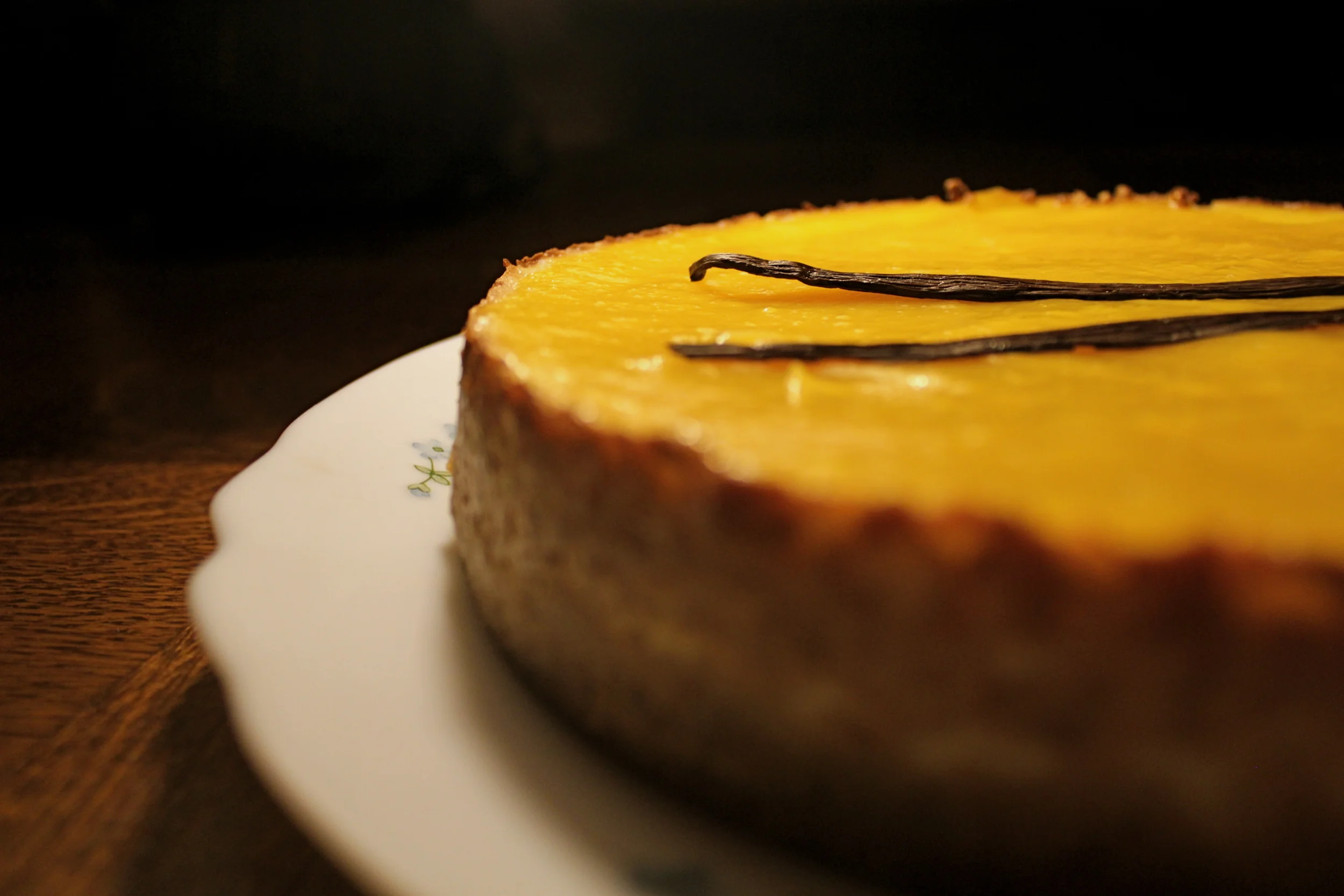 Cheesecake with yellow glaze and vanilla beans on a plate