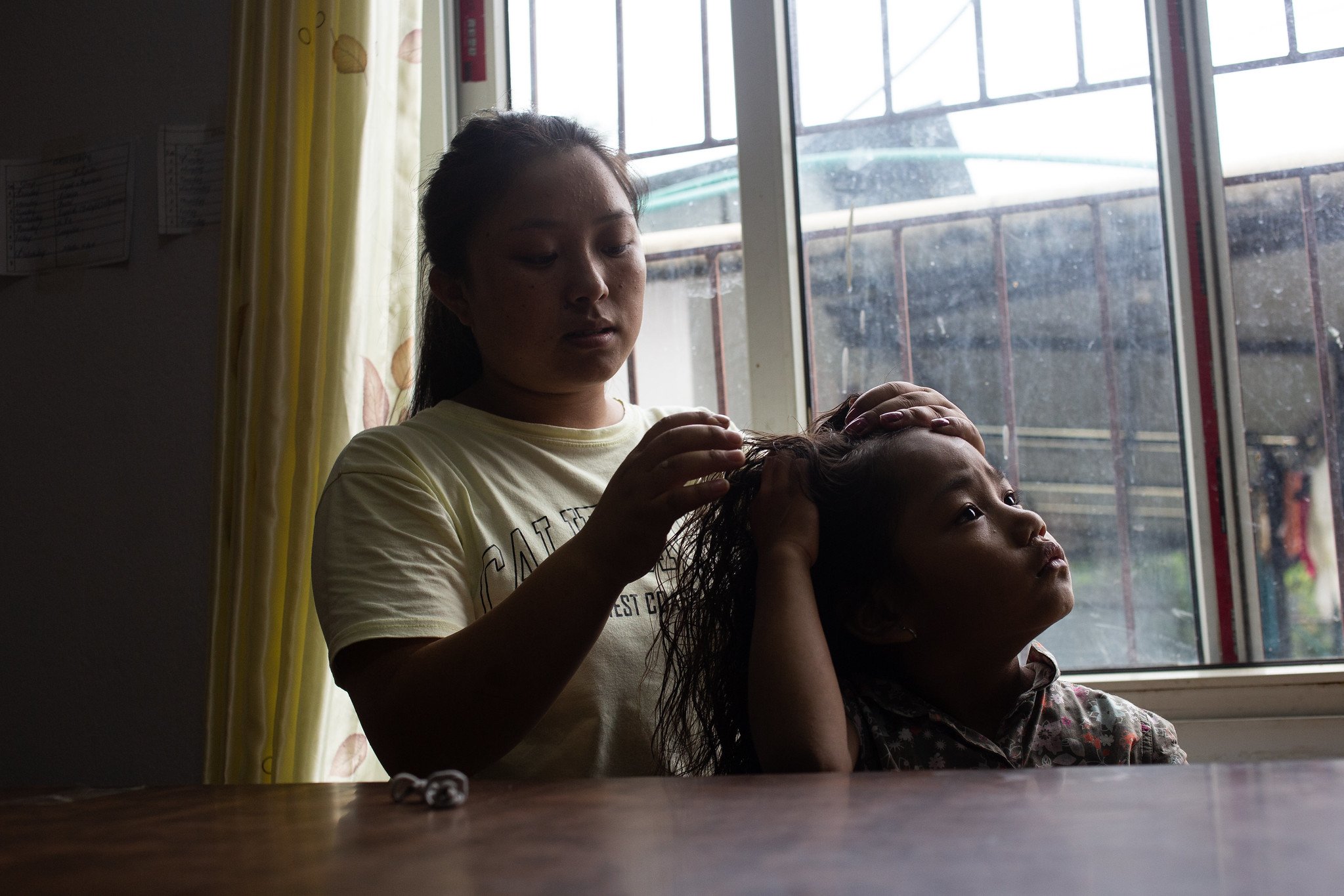  An older girl does the hair of a younger girl at their hostel in Kathmandu. The Small World provides support for their education and accommodation. (Photo by Uma Bista for She’s the First) 