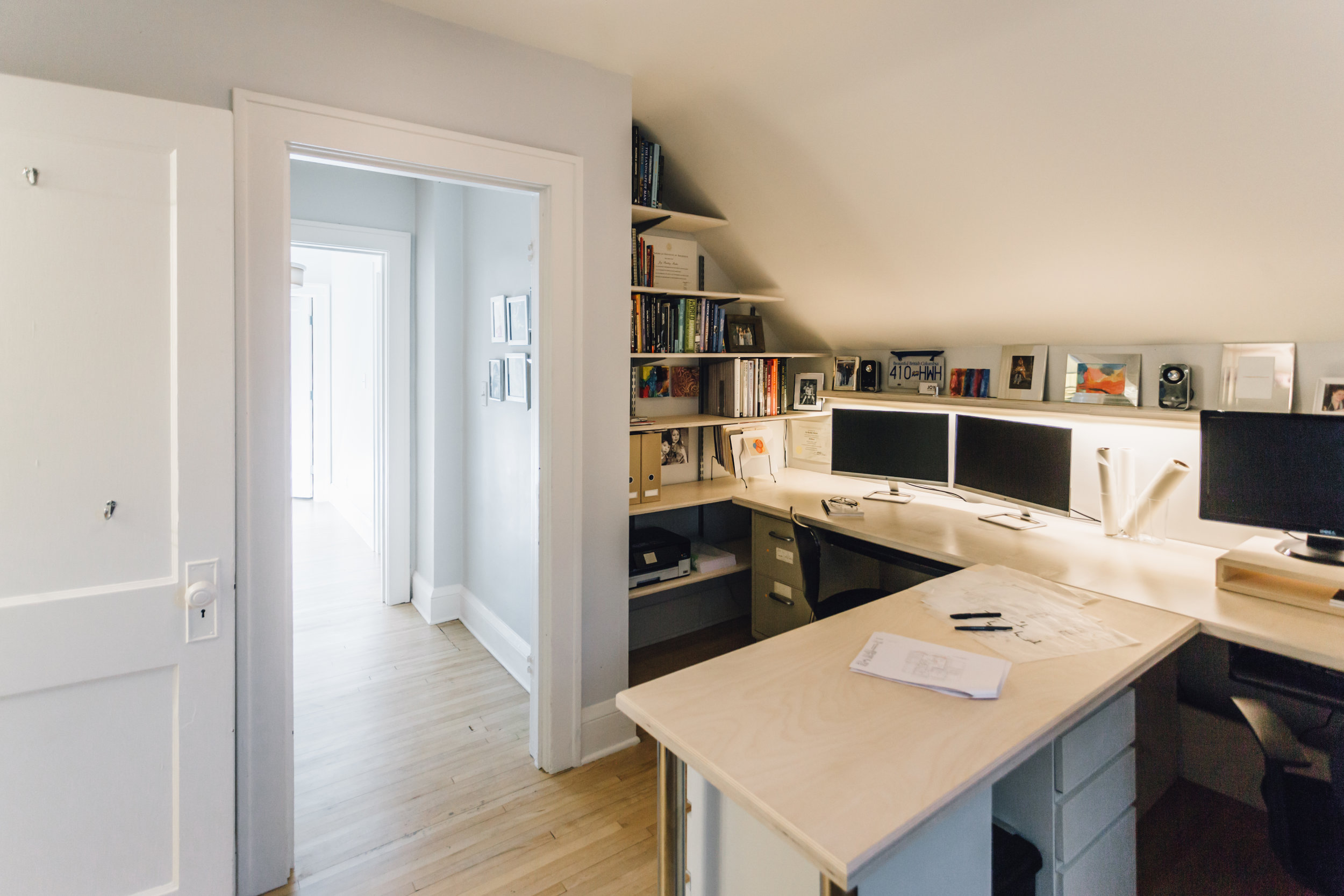 Adjacent to the bathroom, an extra room was converted to a home office with a great view overlooking the oak trees in the backyard. The goal was to create a workspace for two that is stylish and functional, comfortable and efficient. A picture ledge above the desk provides a place for personal mementos and photos; the ledge doubles as a task light with a recessed LED strip light. The former closet access was flipped to be used by an adjacent bedroom, which freed up wall space for library shelving. Another closet was turned into the shower for the adjacent bathroom. The wood used for the desk and shelves is a birch ply with a pickled white stain; details such as a chamfered edge profile and matte finish make the desk surface comfortable and durable. 