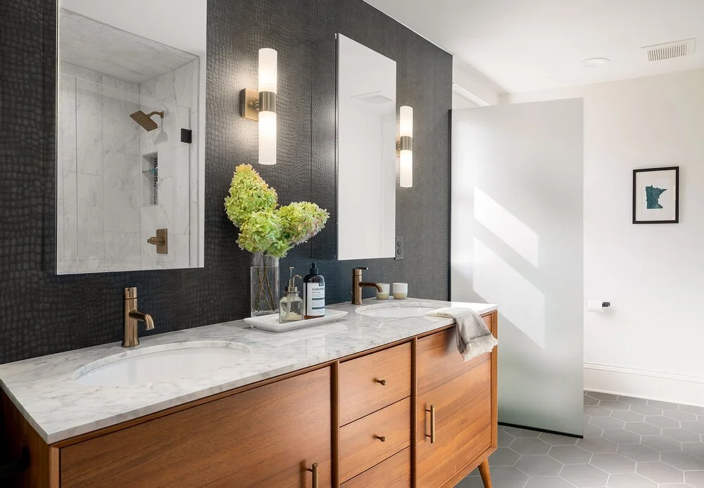 This bathroom renovation left our clients swooning! The warm wood cabinetry pairs perfectly with modern fixtures and faux croc skin wallpaper. By reworking the 2nd floor layout, the architects were able to create a full owners suite bath without addi