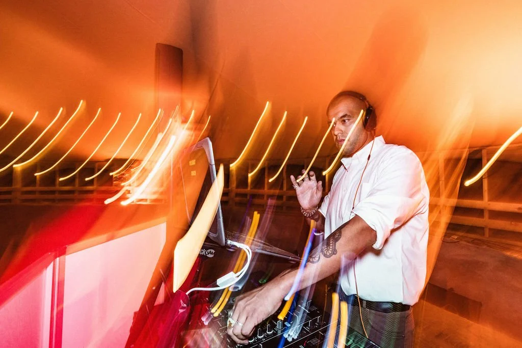 DJ performing with colorful light trails at an event.