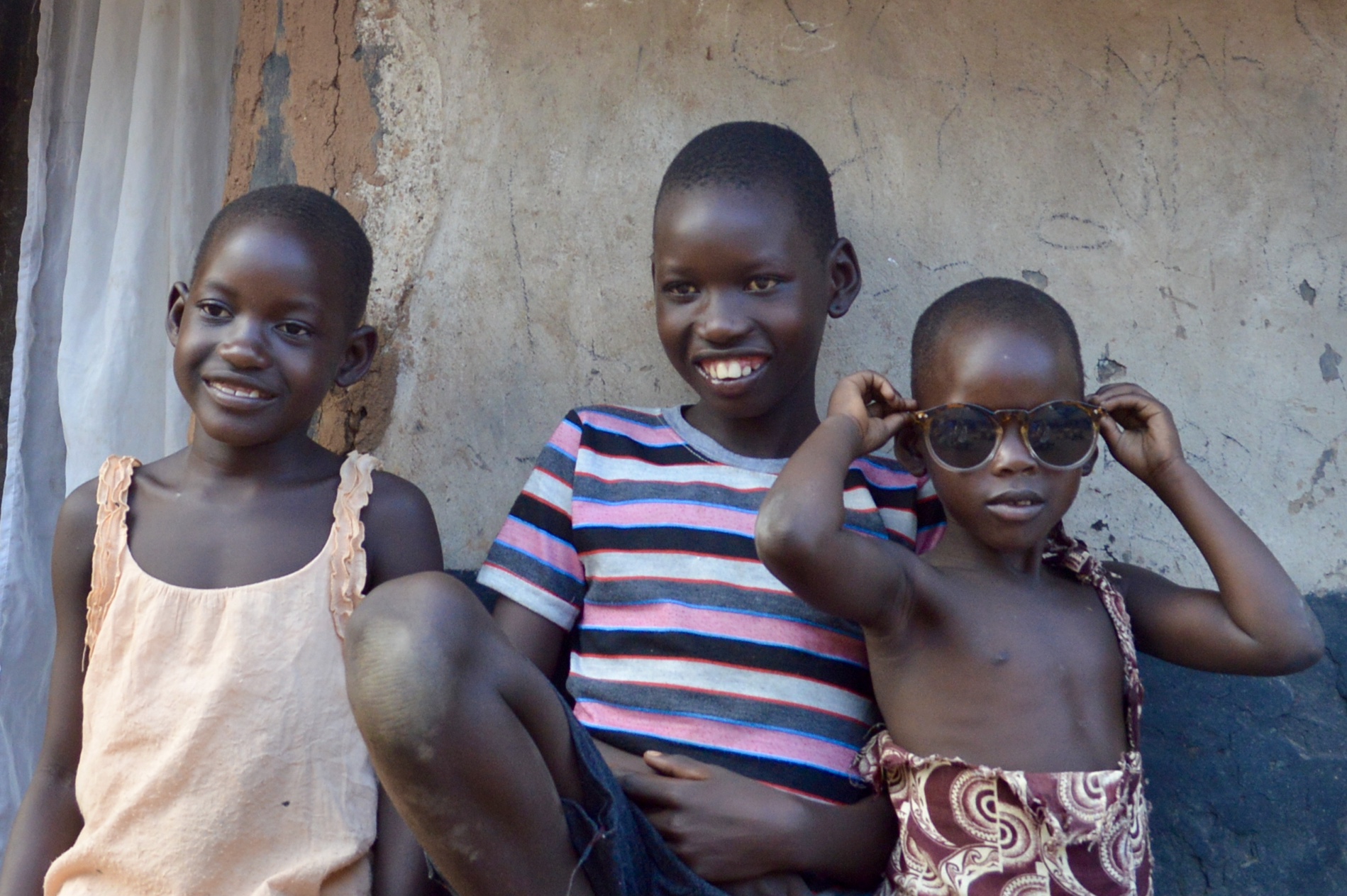 Ronald, confident and smiling with his sisters (also Aphoyo students) outside his home.&nbsp;