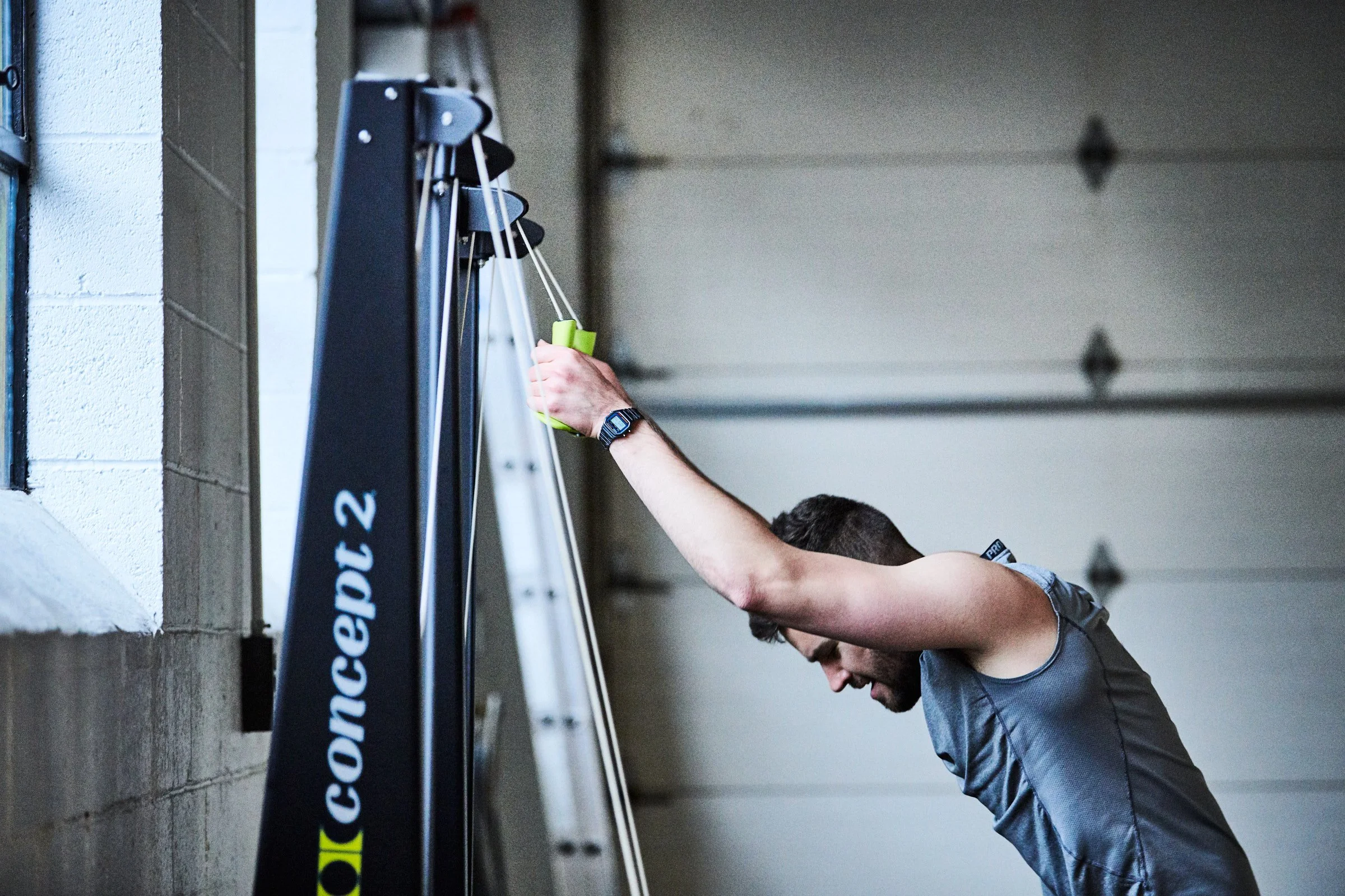 Man cleaning or wiping a peloton exercise bike in a garage or gym setting.