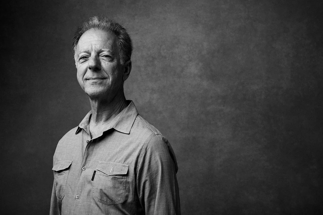 Black and white portrait of an older man with gray hair, wearing a collared shirt, looking confidently at the camera.