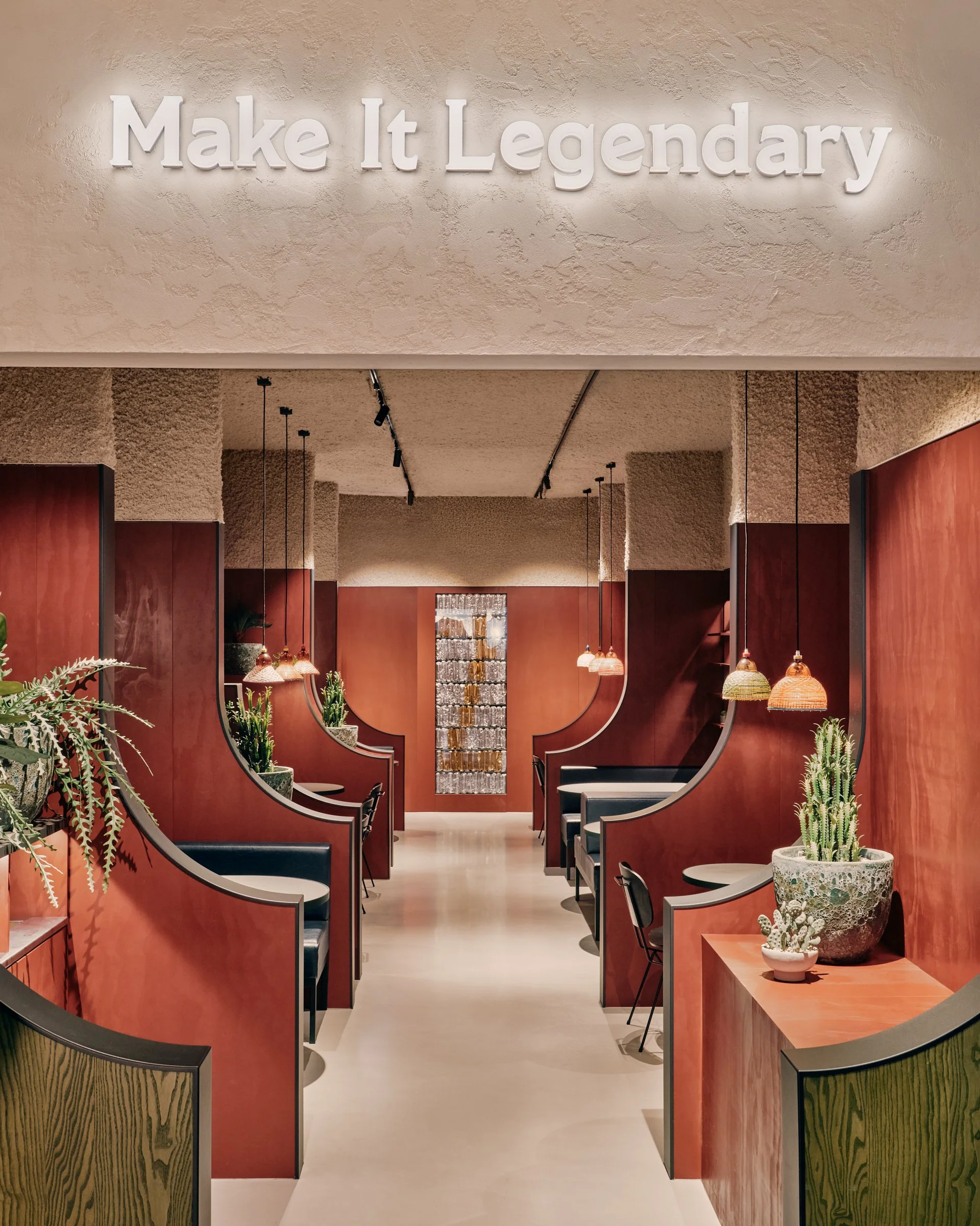  Beyond the counter, visitors step into a rhythmic sequence of seating booths. Their curved profiles frame views through the interior and gradually reveal what lies ahead, turning the length of the space into part of the experience. 