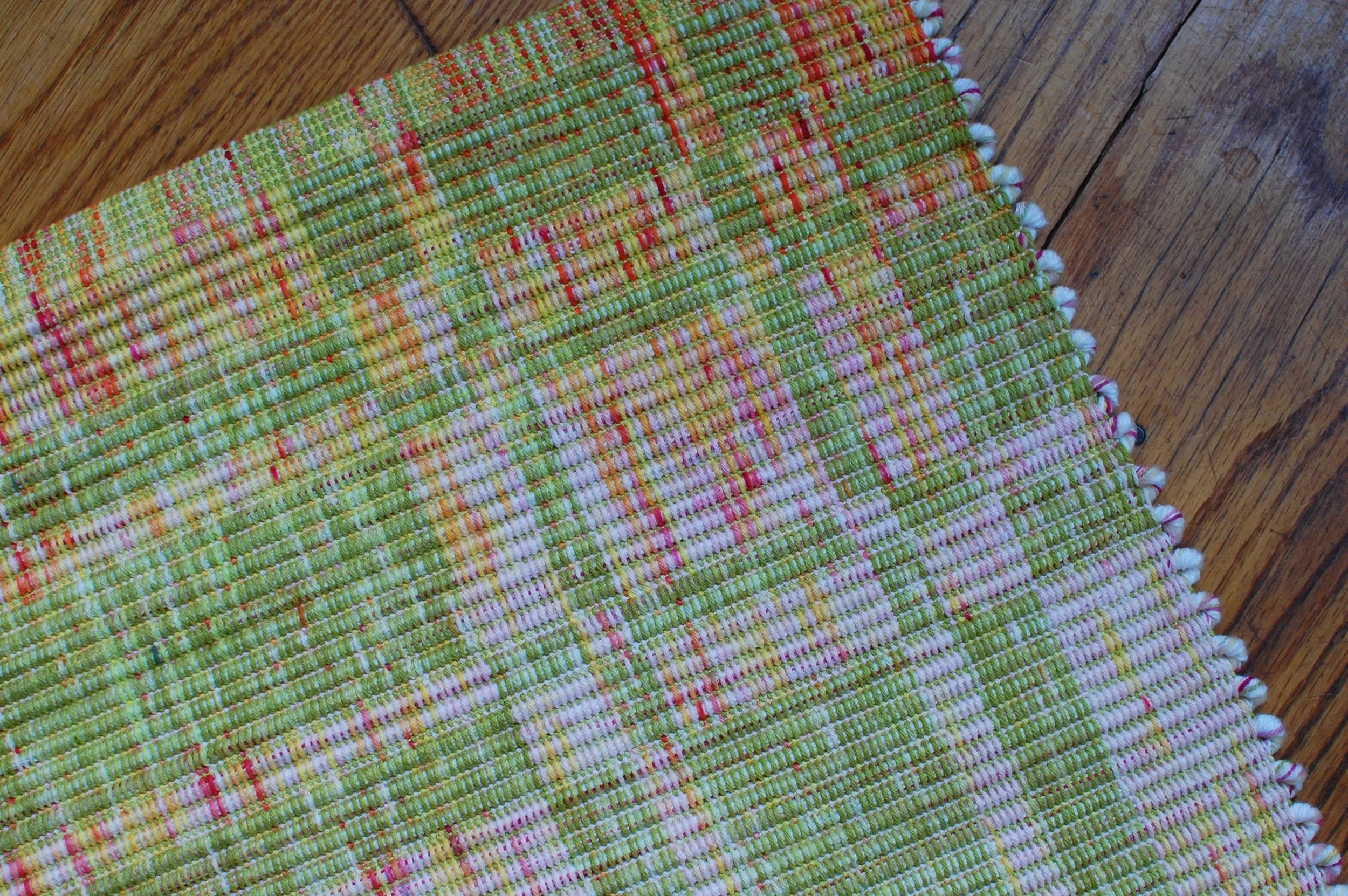 Corner of a handwoven rug with hand-dyed yarn color blocked