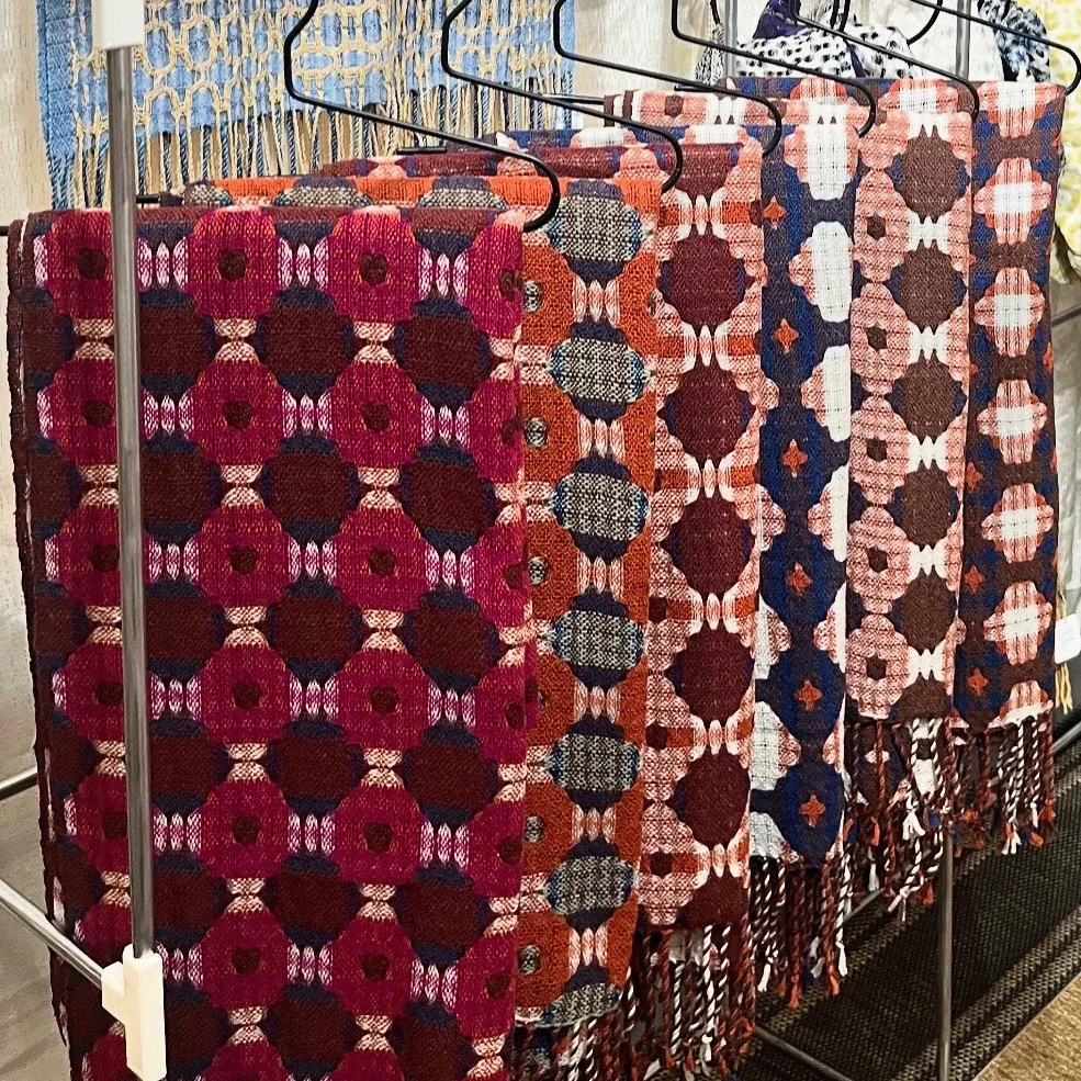 A row of handwoven textiles on a rack.