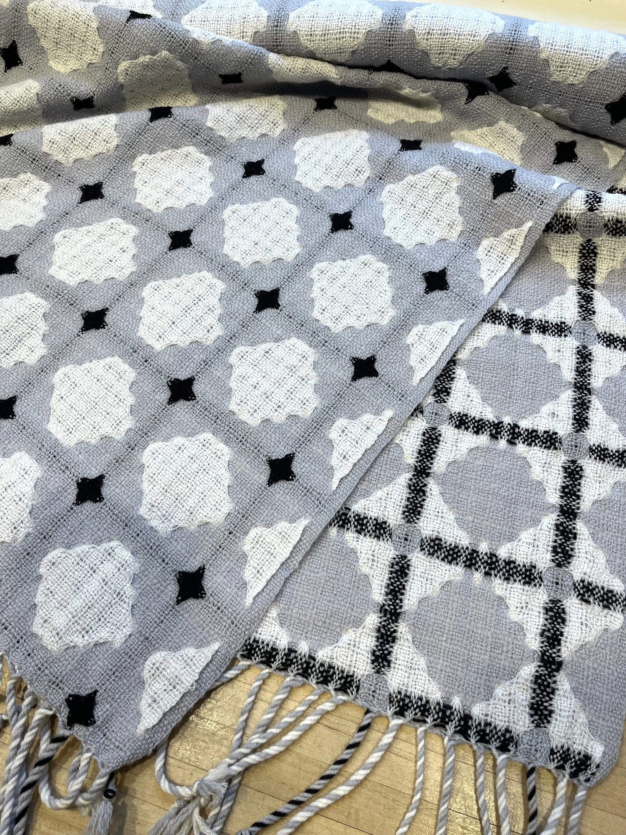 a handwoven textile laying on a table in front of a window.